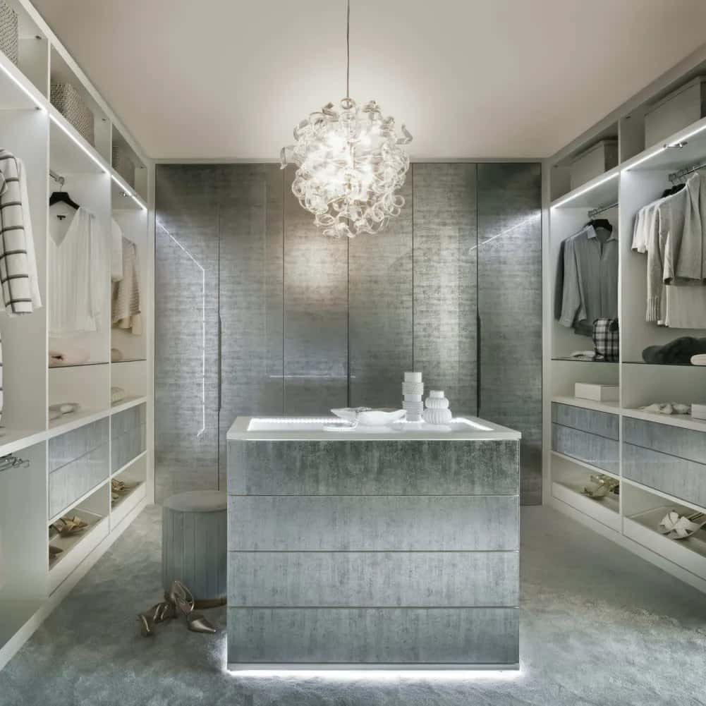 Silver-grey walk-in wardrobe with central island, chandelier, LED lighting and white shelving