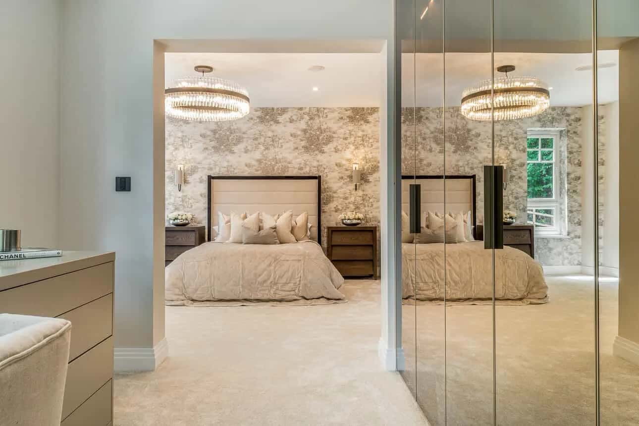 Mirrored wardrobe doors reflecting a luxurious bedroom with chandelier and upholstered bed