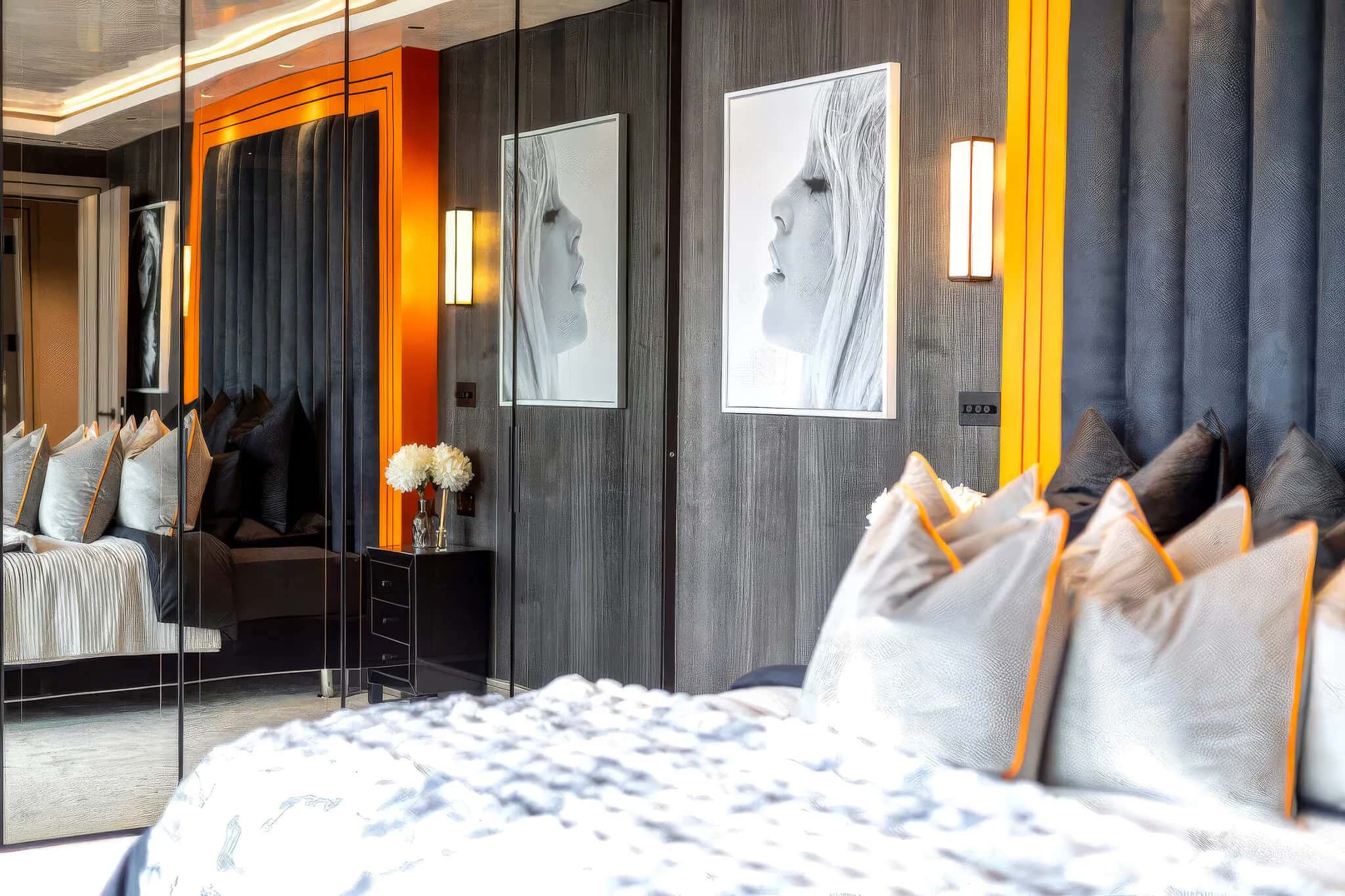 Bedroom with orange-framed padded headboard, wood-panelled wall and mirrored wardrobe doors