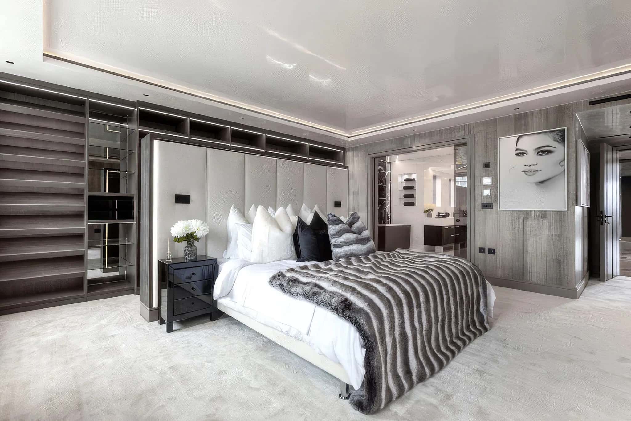 Master bedroom with grey padded headboard, fitted open shelving and fur bed throw