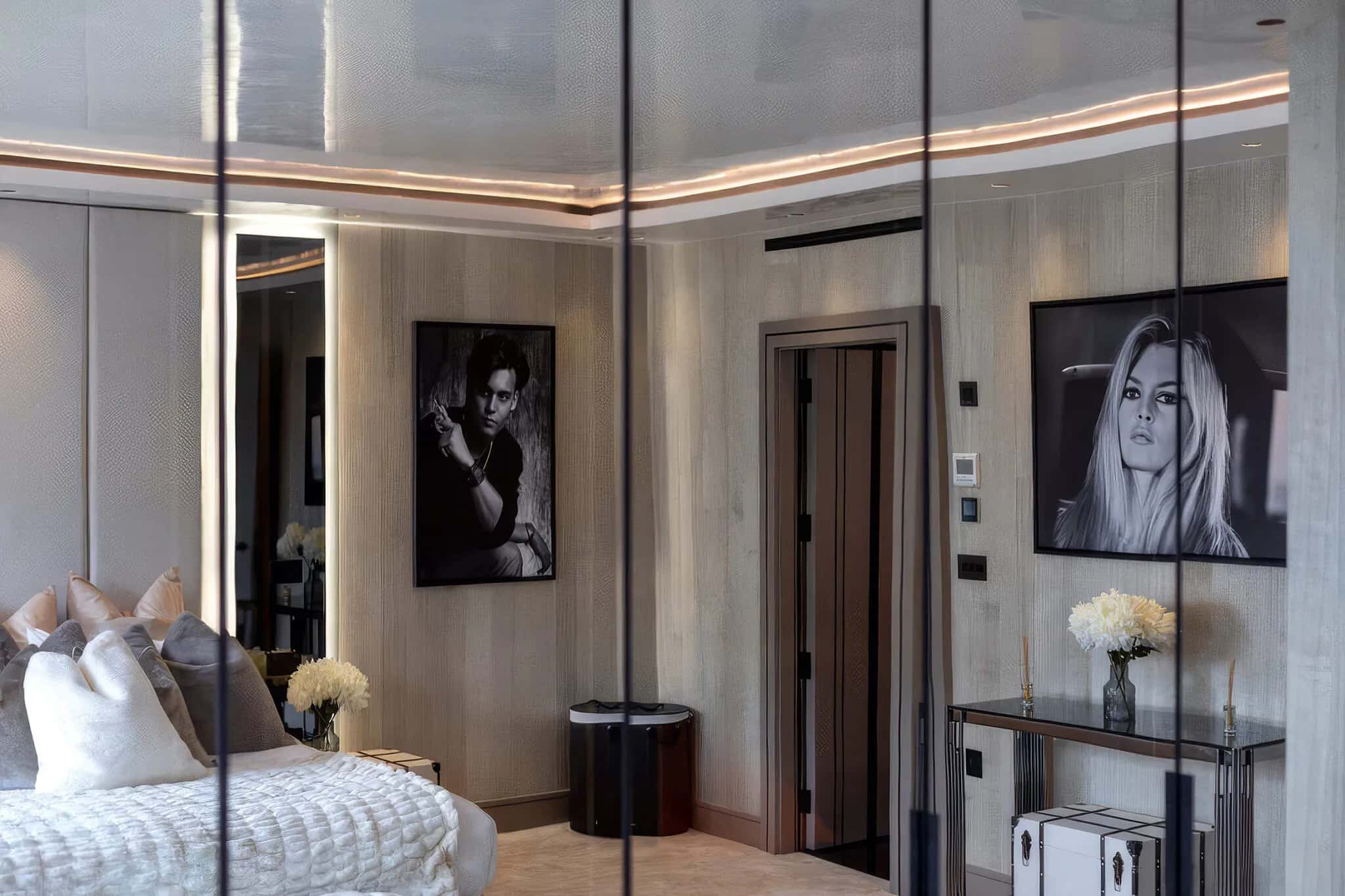 Bedroom with mirrored wardrobe doors reflecting the room, pale wood panelling and framed portraits