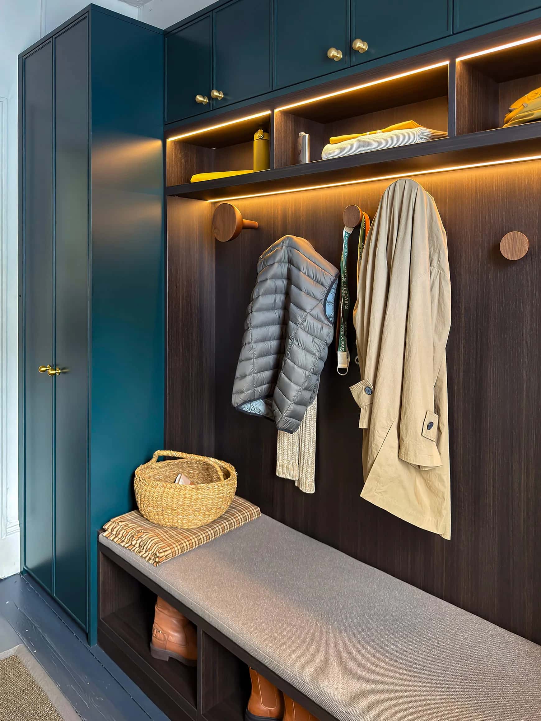 Boot room with teal fitted cupboards, dark oak coat hooks, LED lighting and a built-in cushioned bench