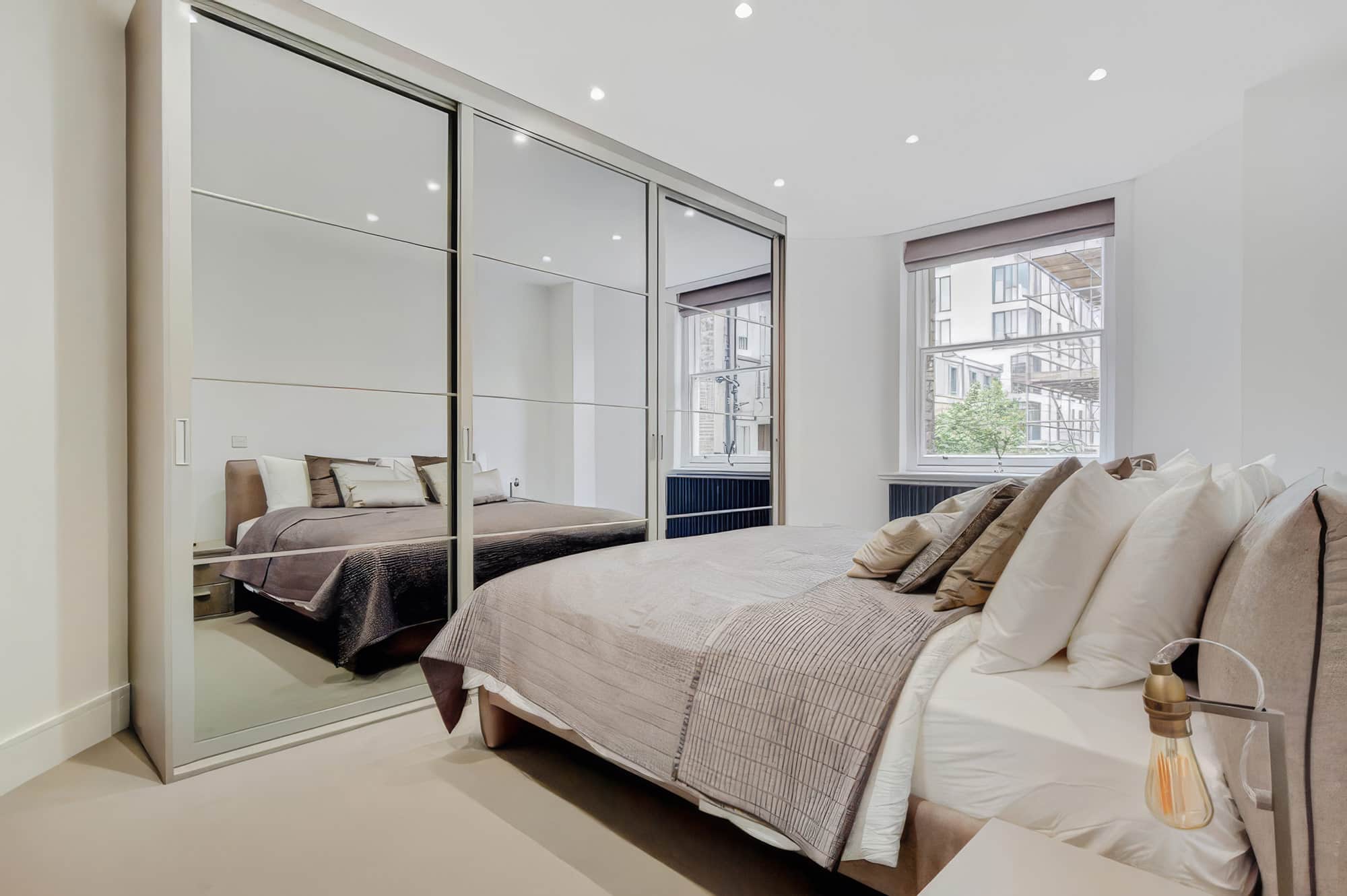 Full-height mirrored wardrobes in a bright bedroom
