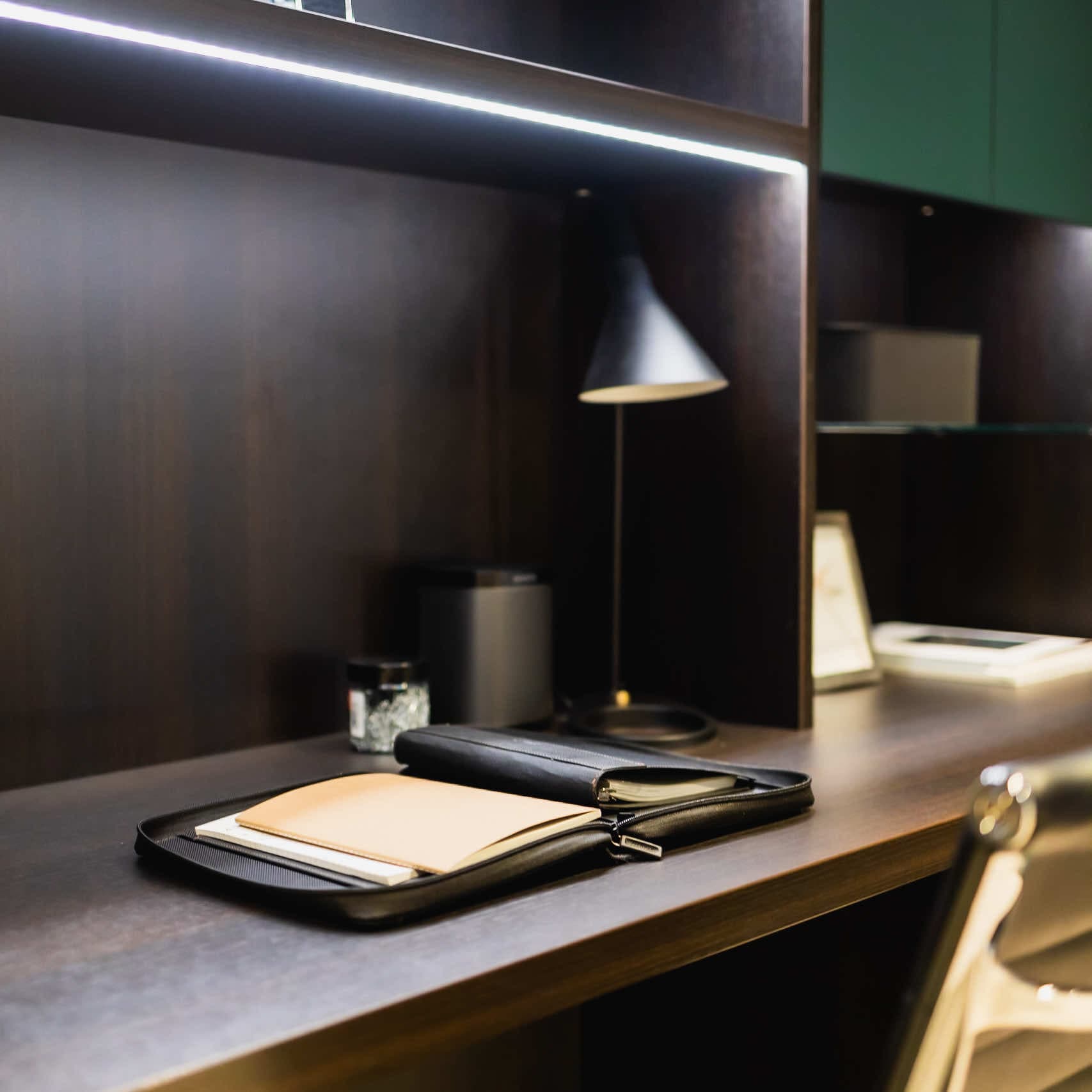 Dark wood desk with LED strip lighting, desk lamp and leather folder