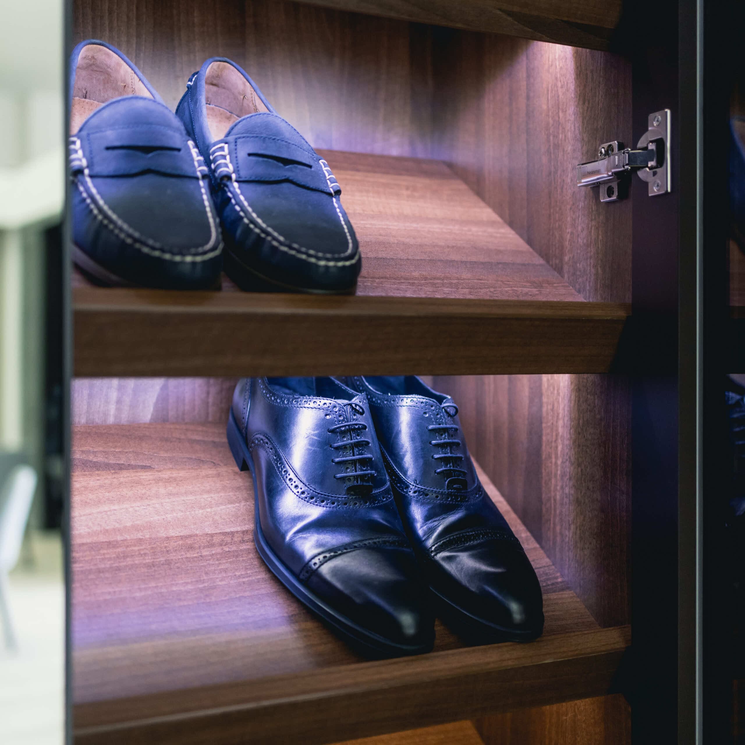 Angled shoe shelves with LED lighting displaying loafers and brogues