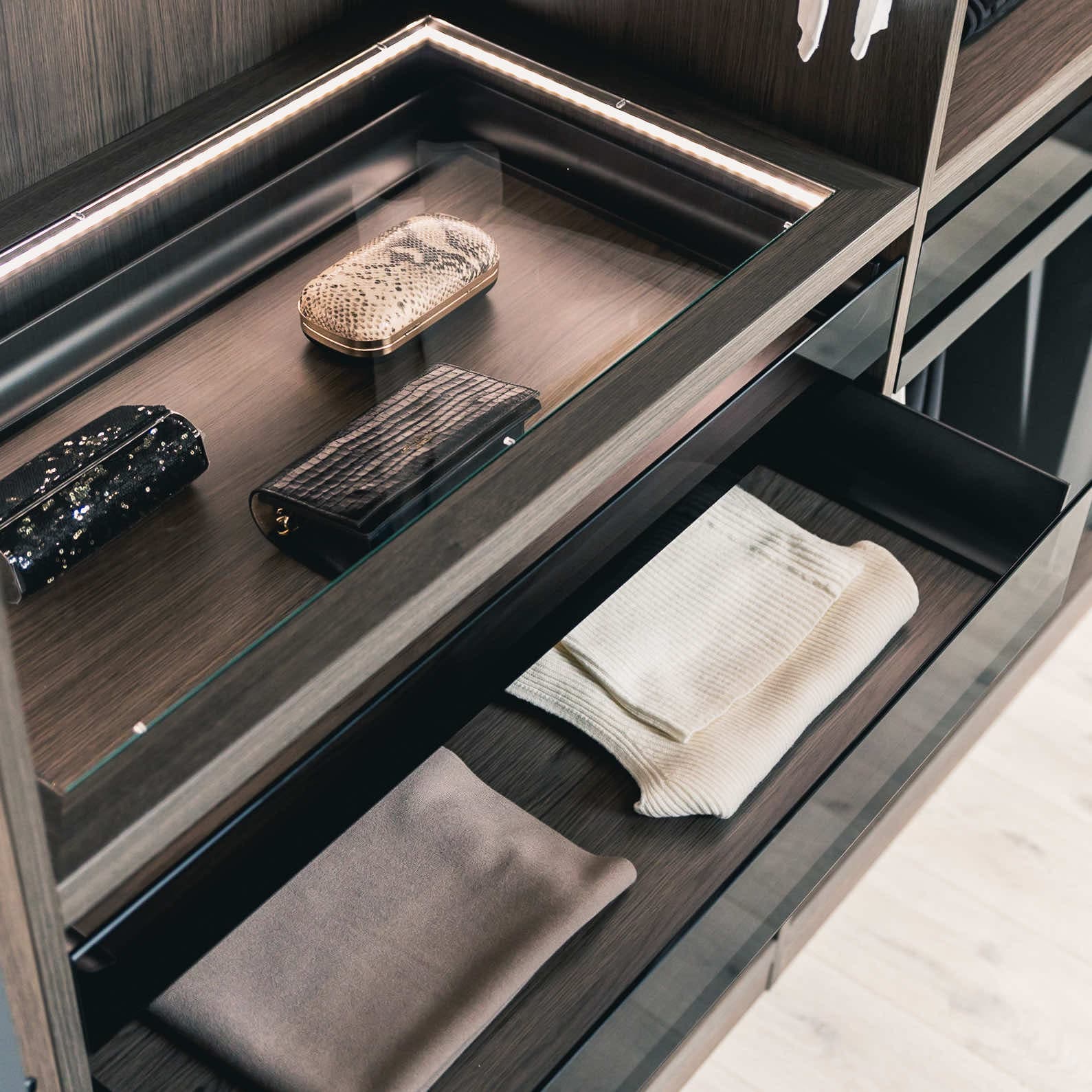 Glass-topped wardrobe drawer with LED edge lighting displaying clutch bags