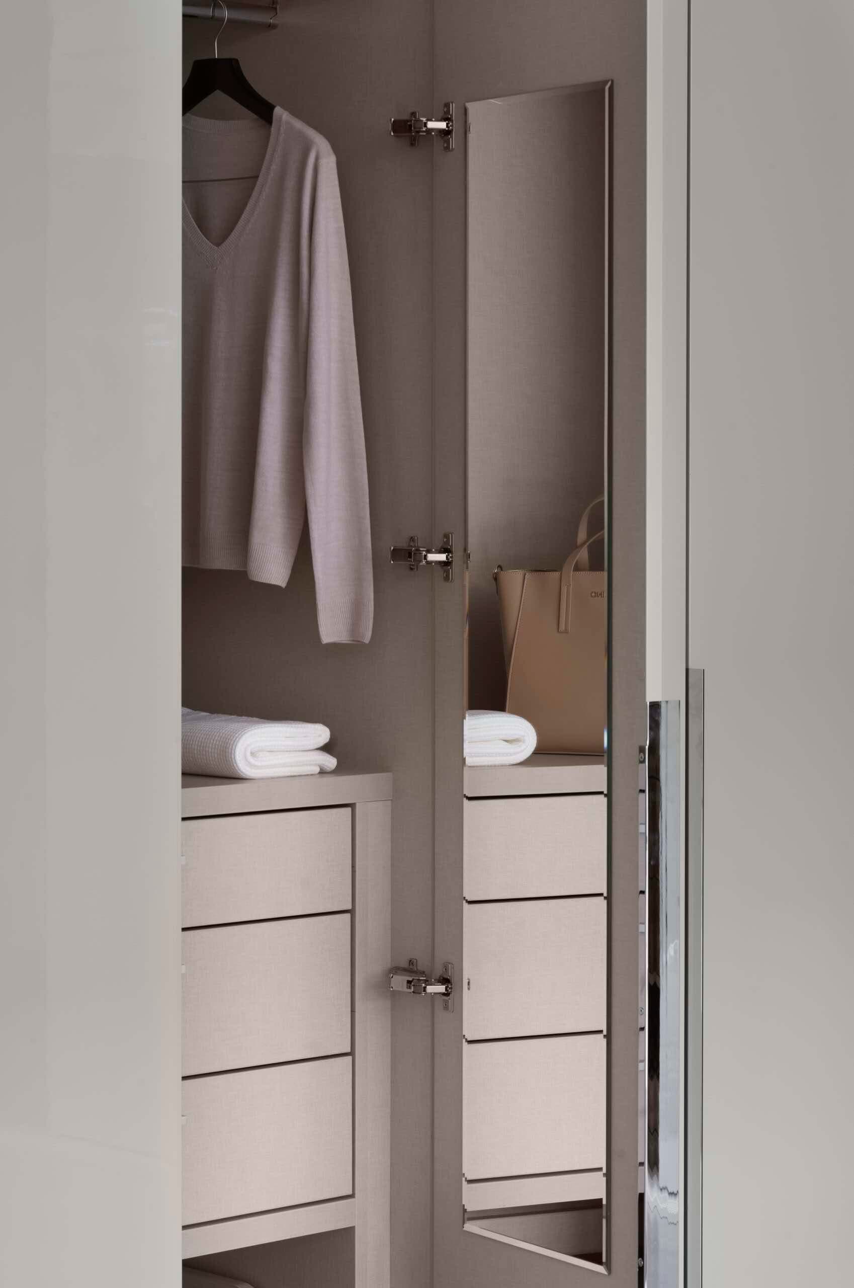 Internal wardrobe door mirror beside hanging space and drawers