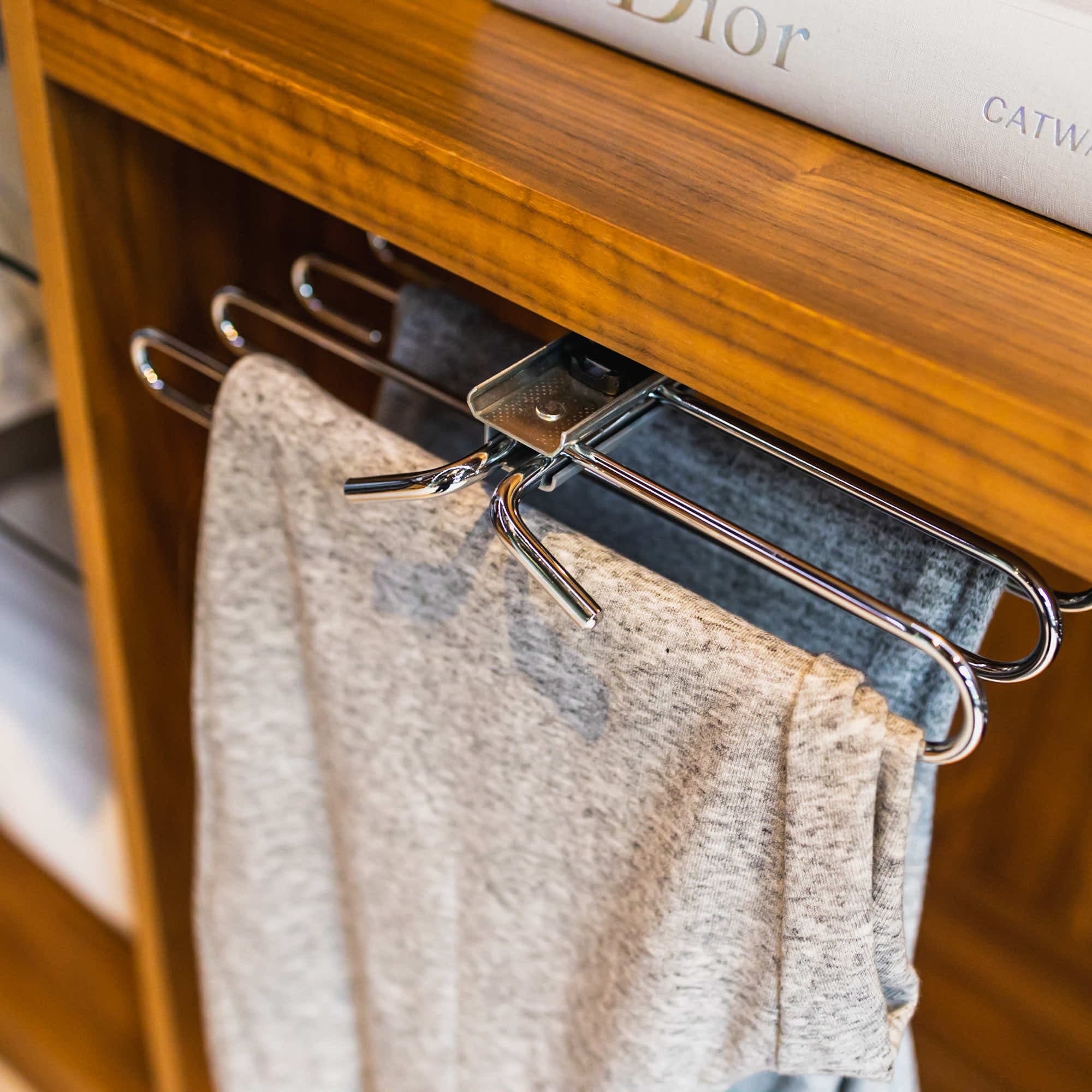 Pull-out chrome trouser rack in a walnut wardrobe holding grey trousers