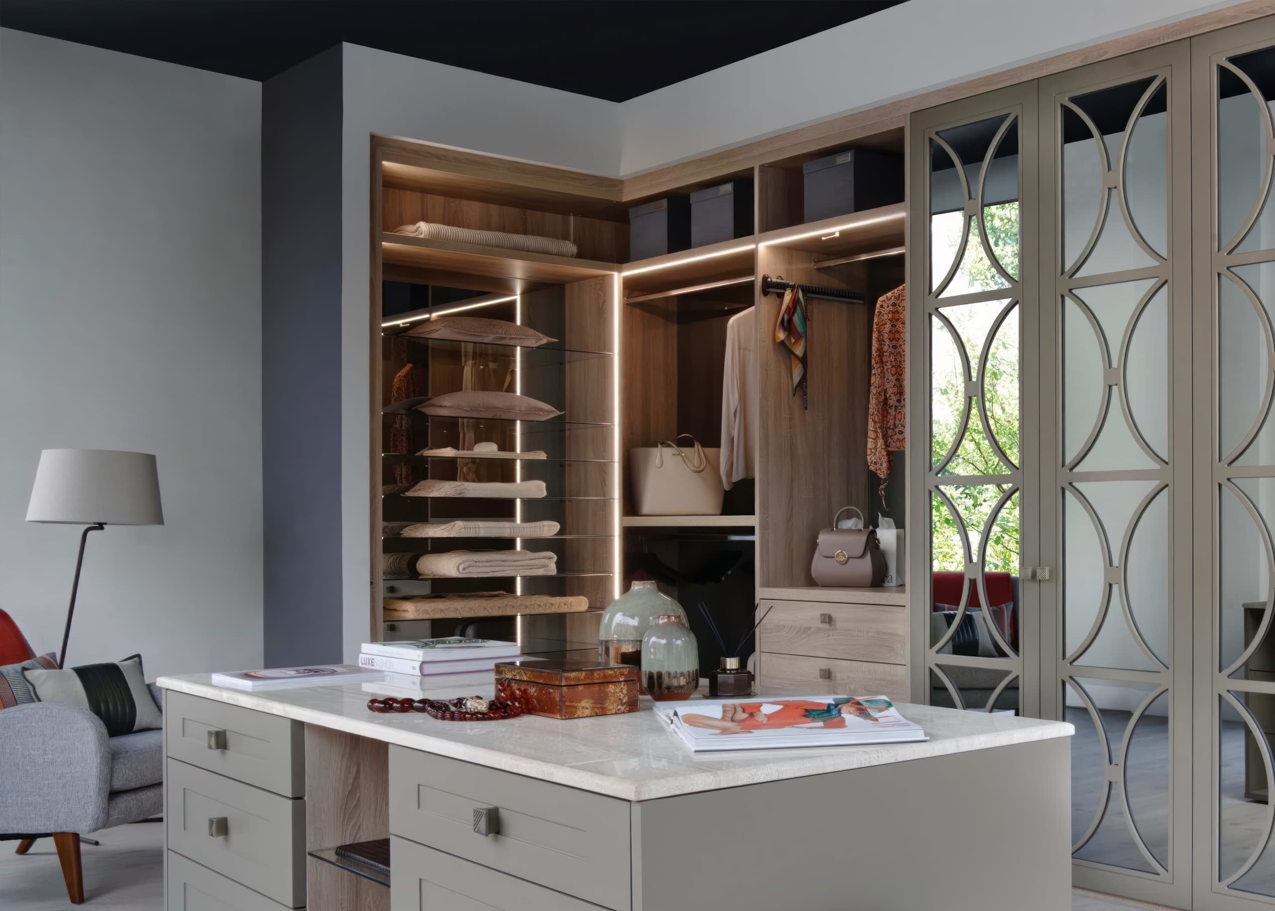 Walk-in wardrobe with marble-topped island and circle-pattern mirrored doors in grey