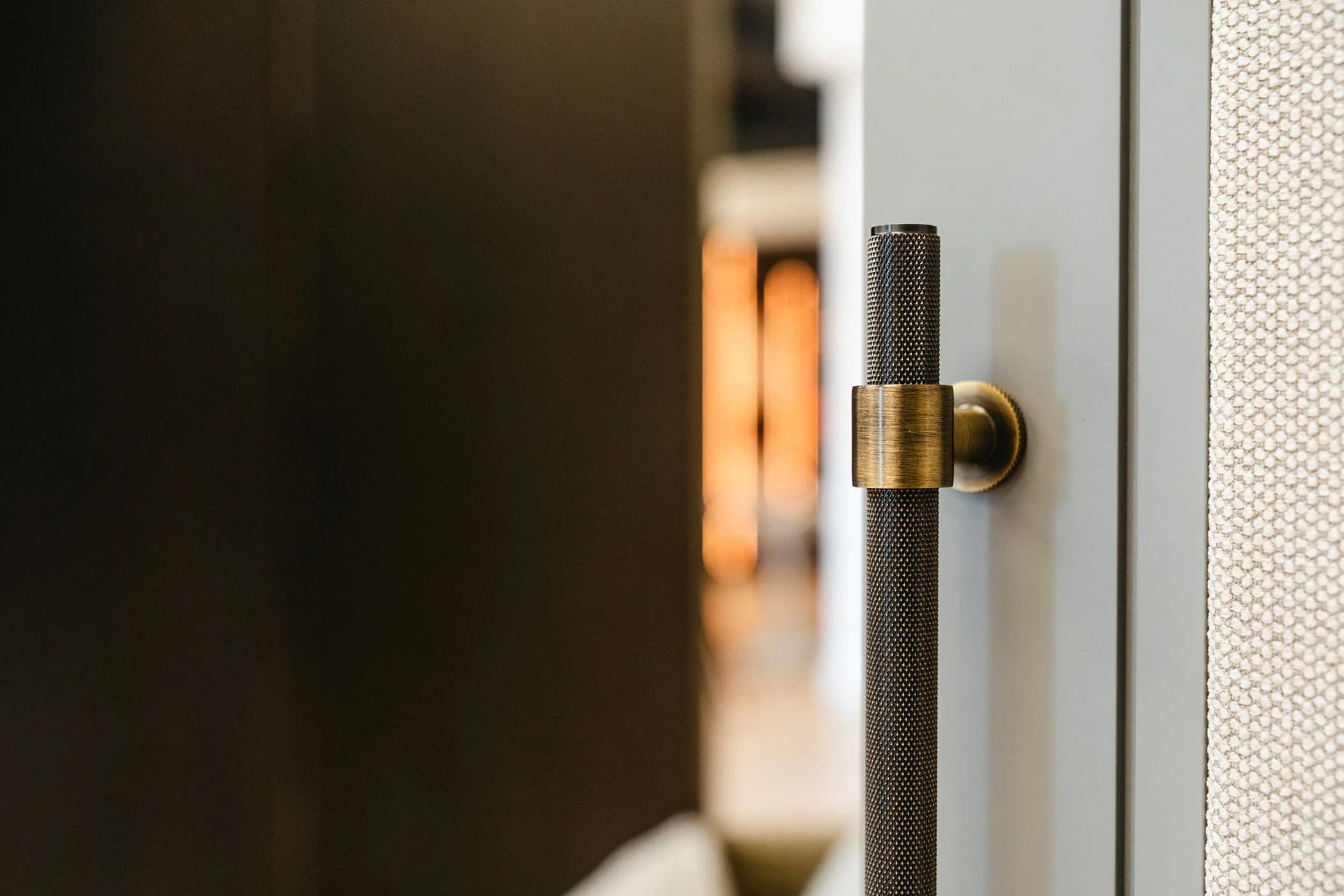 Close-up of a knurled bronze T-bar handle on a grey-blue wardrobe door