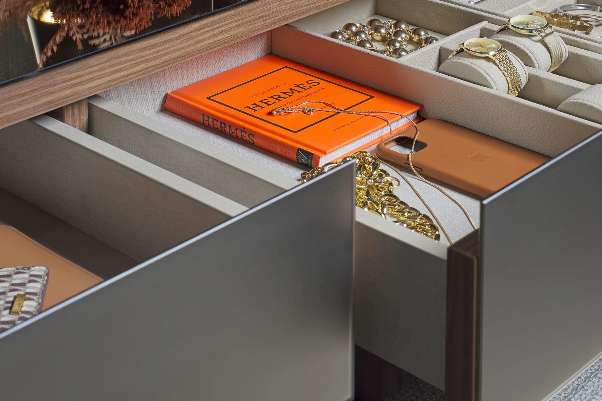 Open jewellery and watch drawers in grey, with orange book and gold accessories