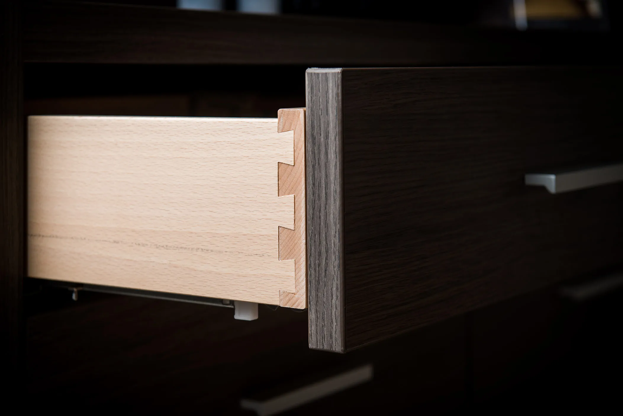 Open drawer showing solid wood dovetail joints in a dark oak-effect wardrobe