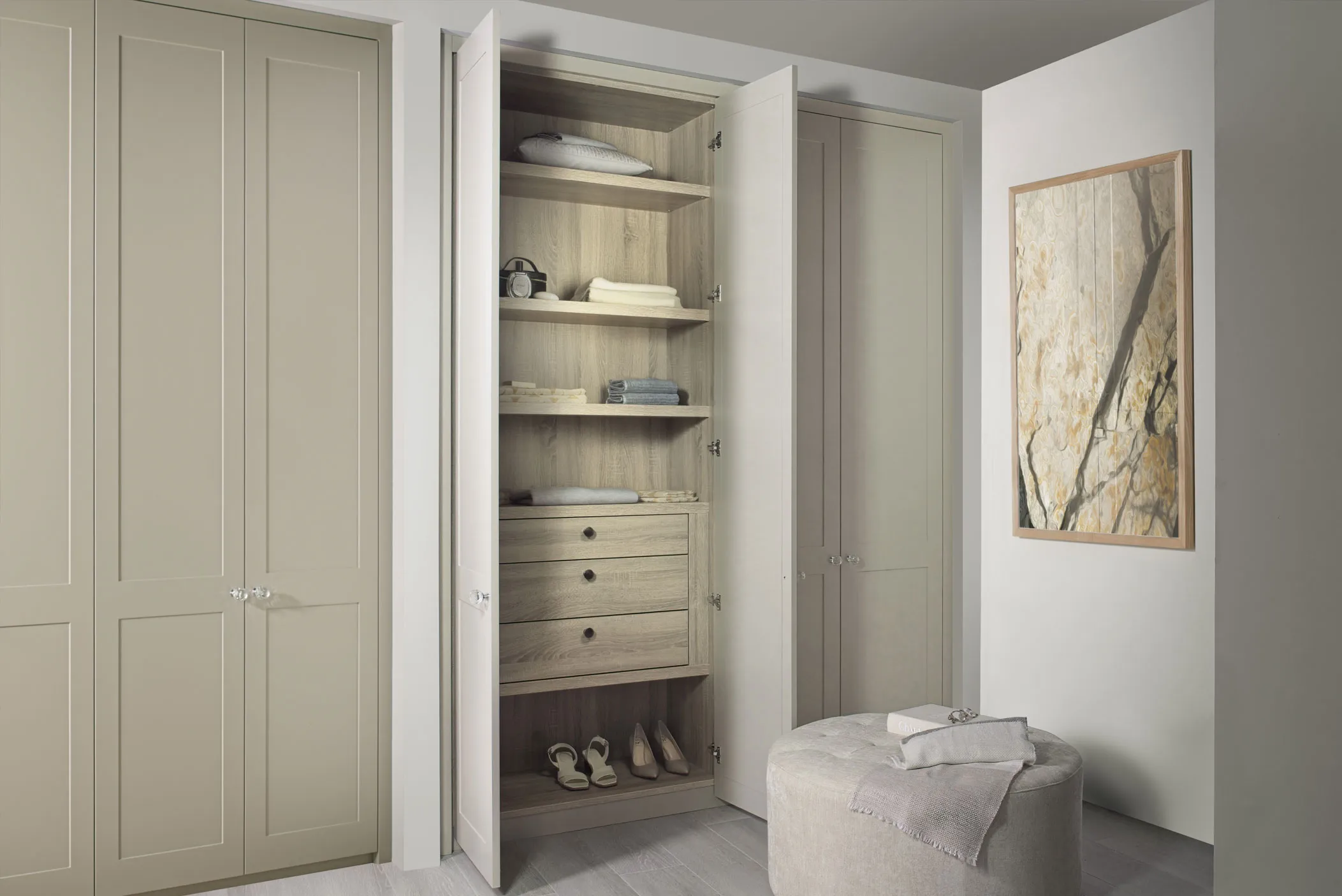 Open fitted wardrobe in stone shaker doors with oak shelving, drawers and shoe storage