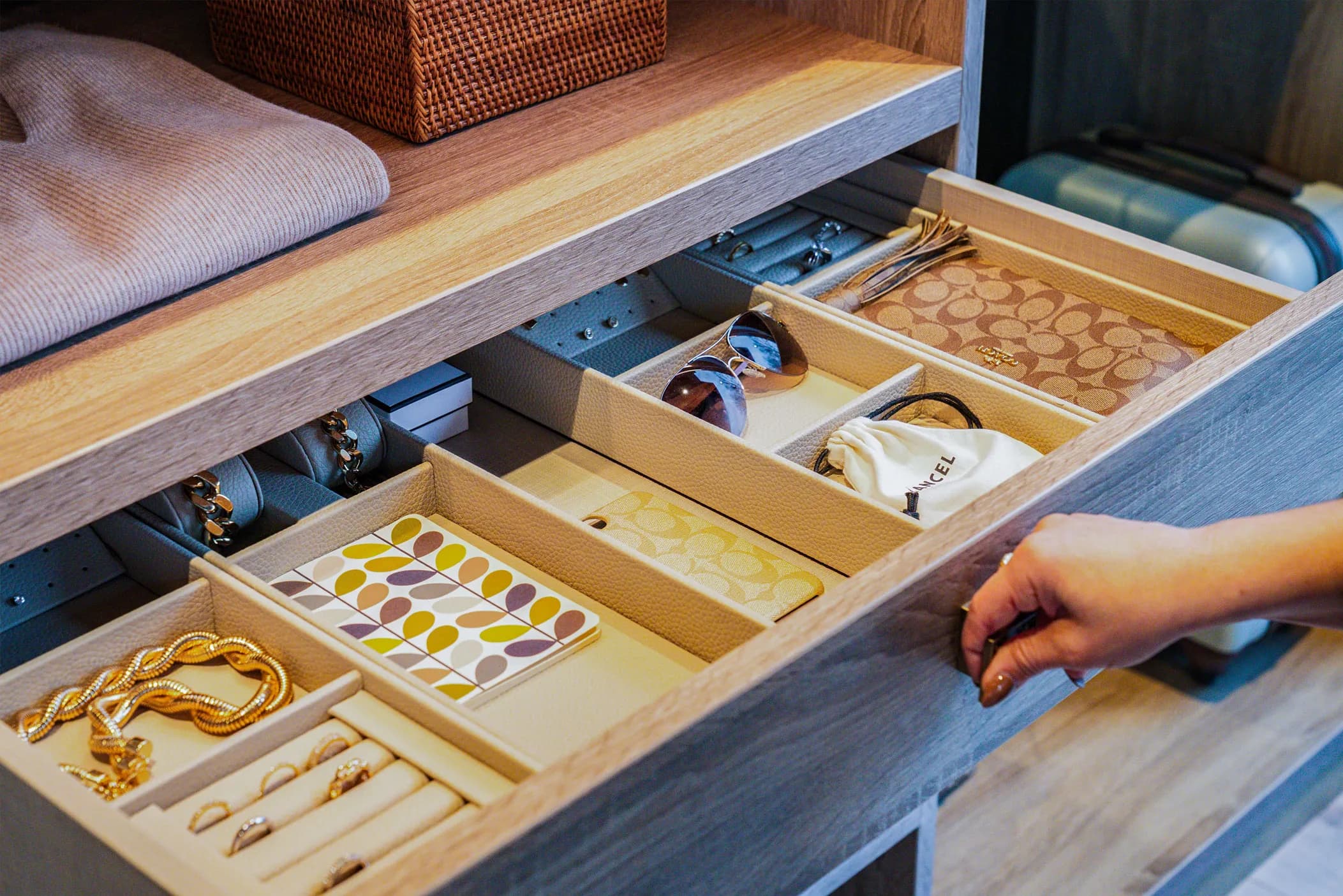 Open drawer with jewellery, sunglasses and accessory dividers in a light oak wardrobe
