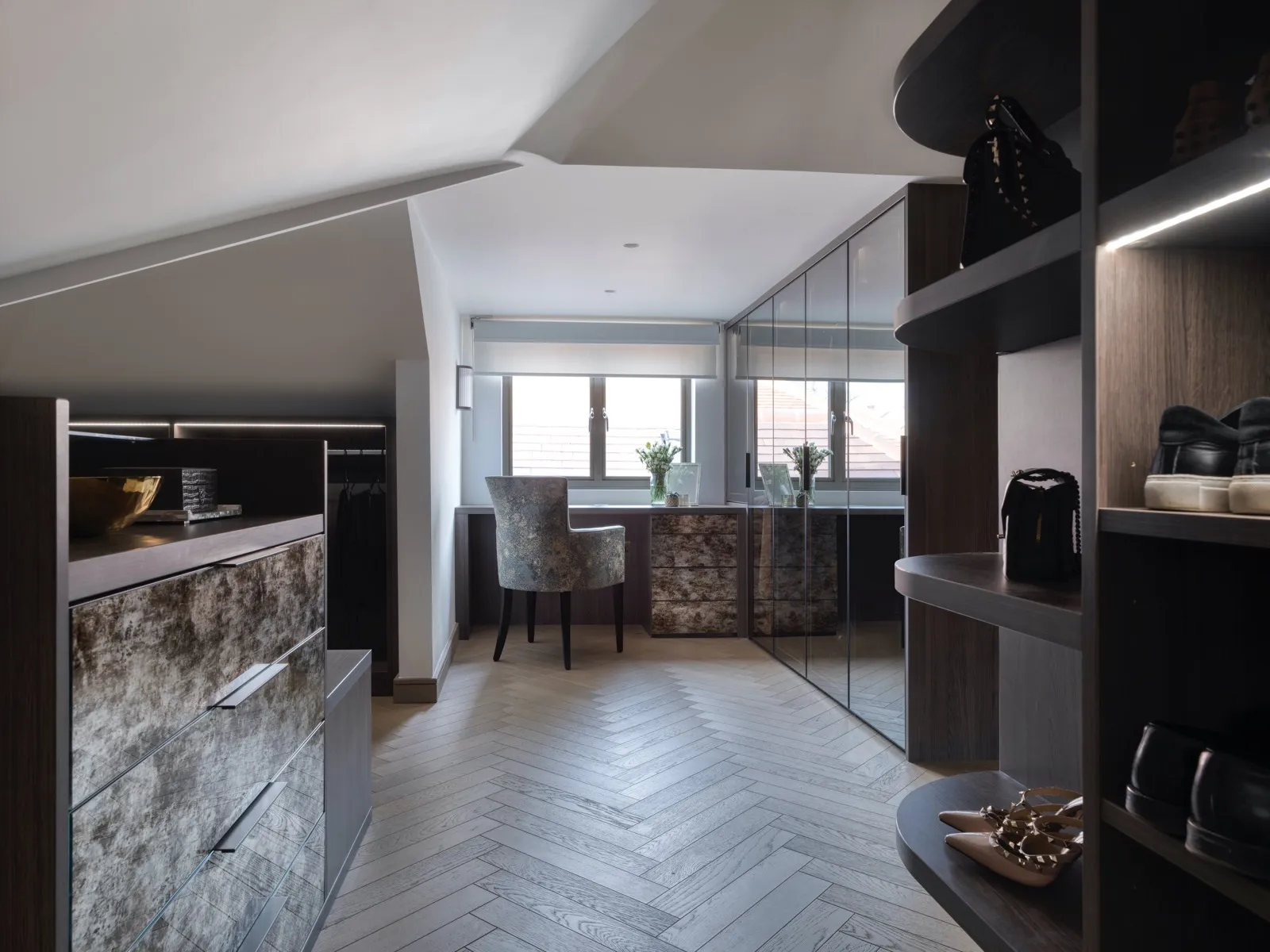 Attic dressing room with mottled glass drawers, mirrored wardrobes and a desk under a sloping ceiling
