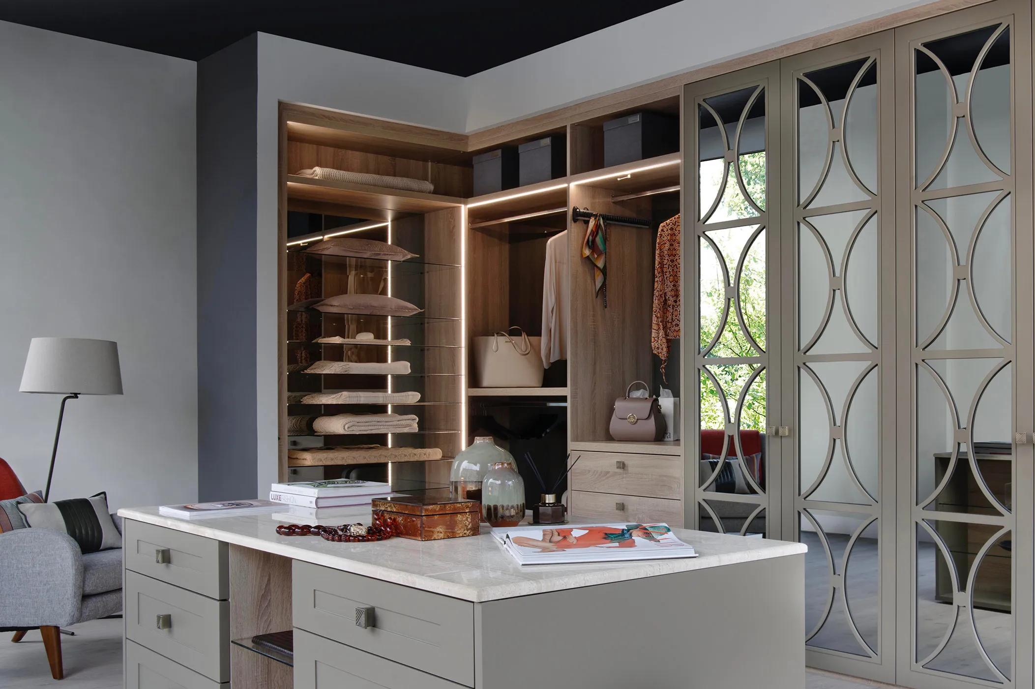 Dressing room with central island unit, oak shelving and fretwork mirrored wardrobe doors