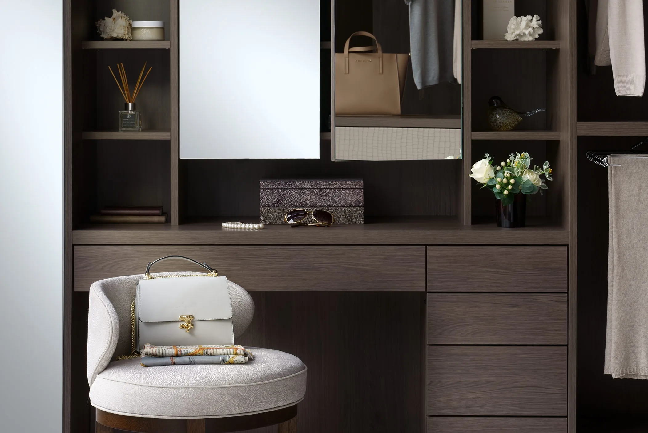 Dressing table with drawers, mirror and open shelves in a dark oak wardrobe, with upholstered stool