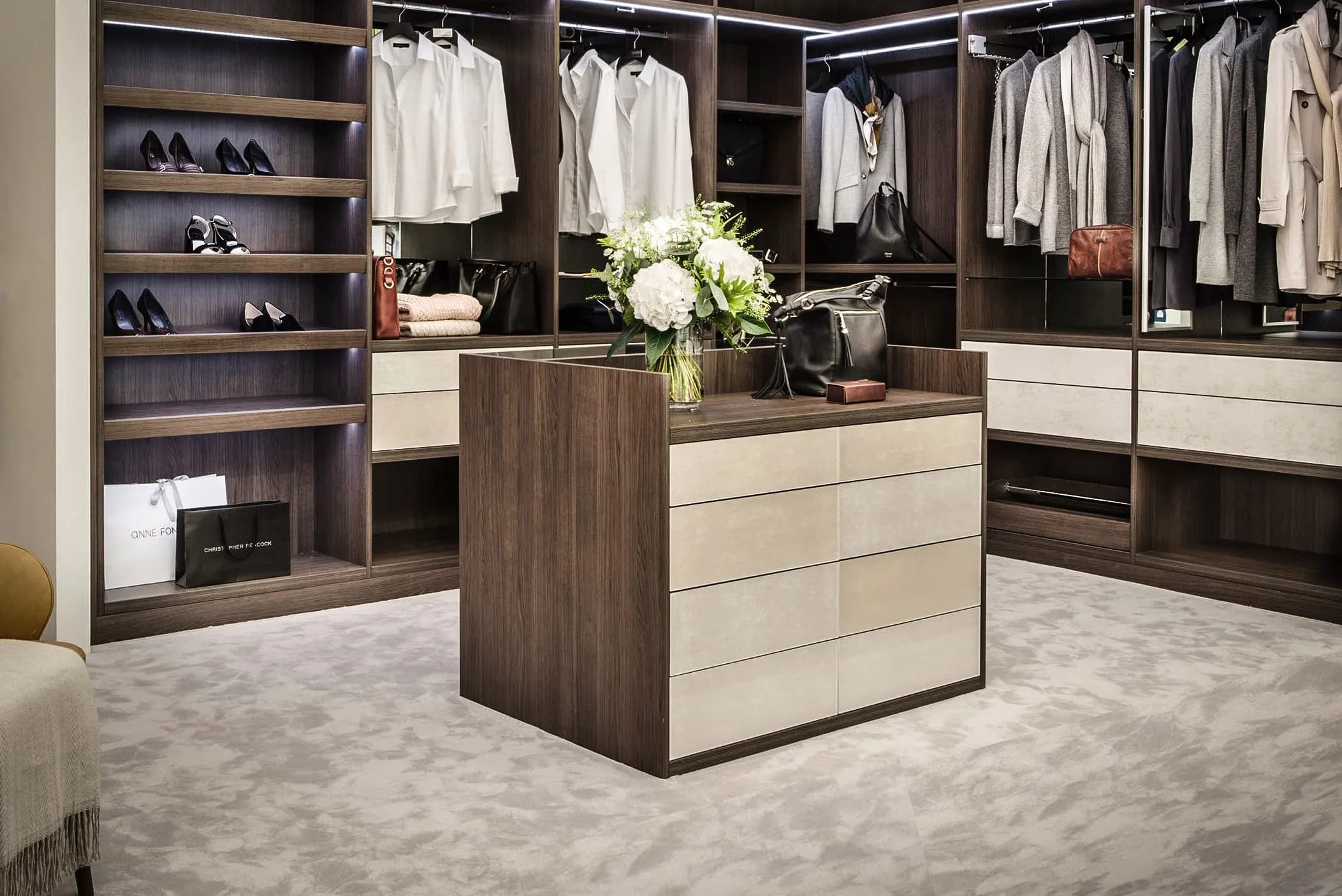 Walk-in wardrobe with walnut island unit with cream drawer fronts, hanging rails and shoe shelves