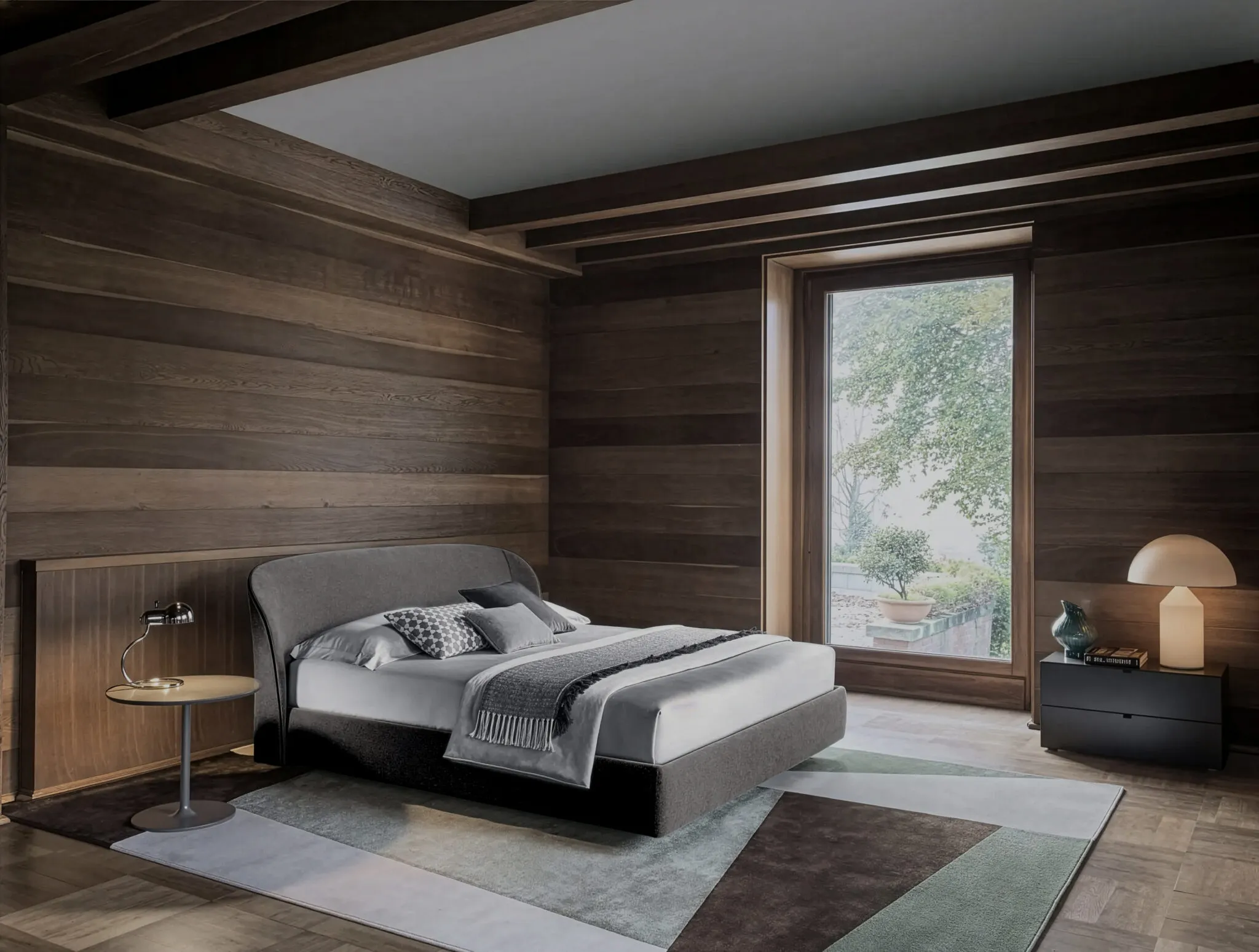 Upholstered bed with grey headboard in a bedroom with timber-clad walls and large window
