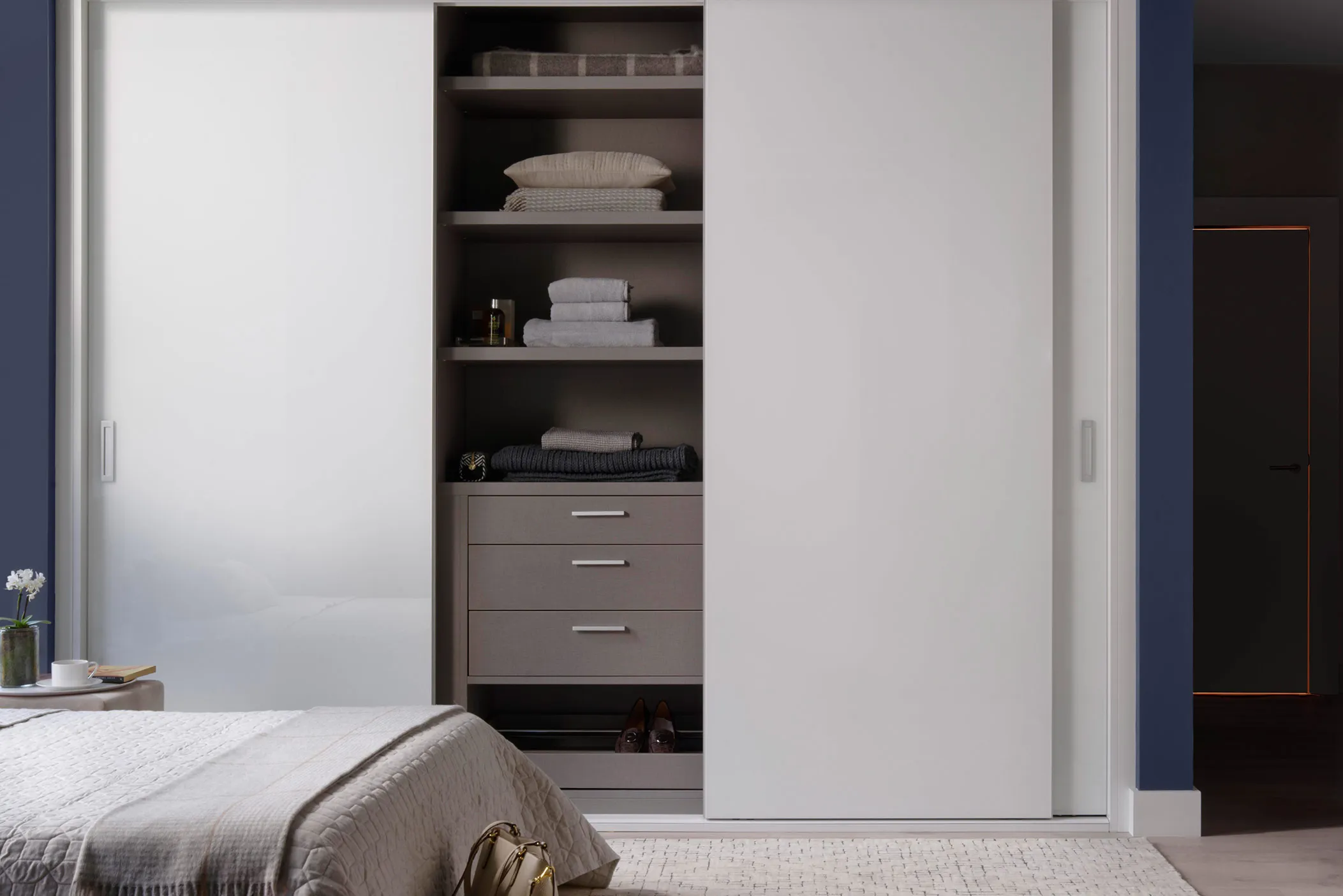 Bedroom with white sliding door wardrobe open to shelves and drawers