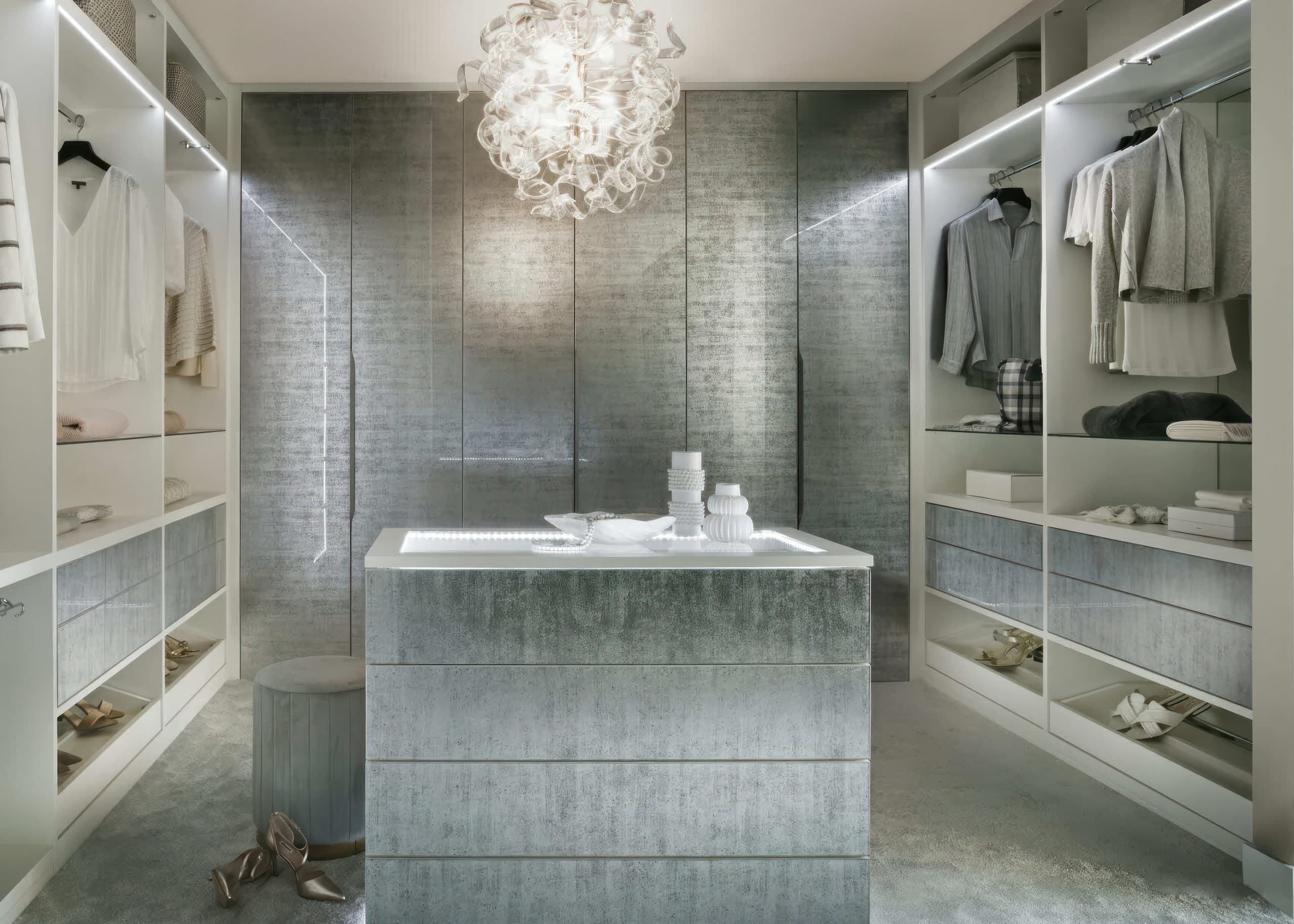 Walk-in wardrobe with decorative glass doors, central island and crystal chandelier