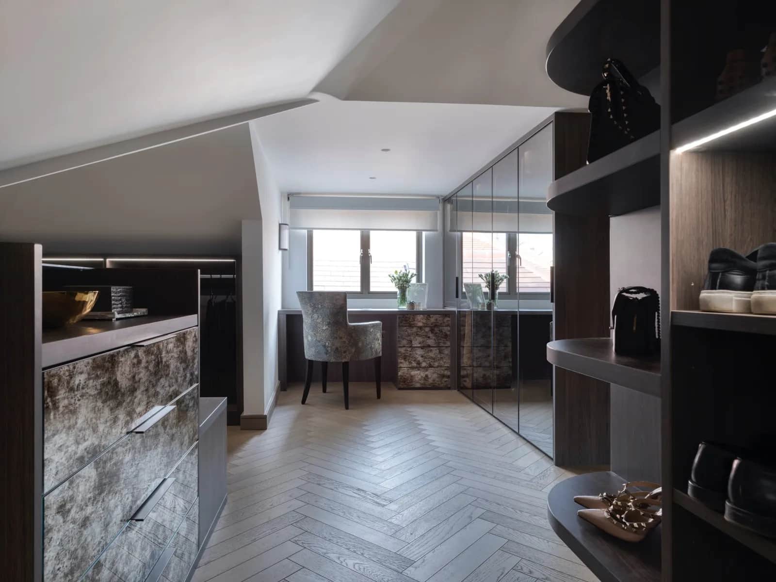 Attic dressing room with mottled glass drawers, mirrored wardrobes and a desk under a sloping ceiling