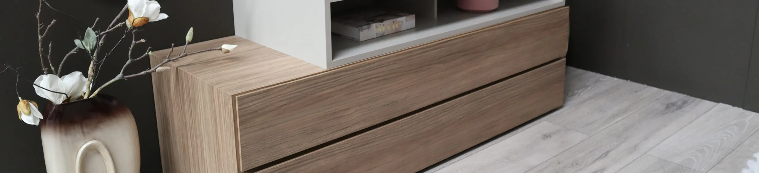 Walnut-effect chest of drawers beside a vase of white flowers