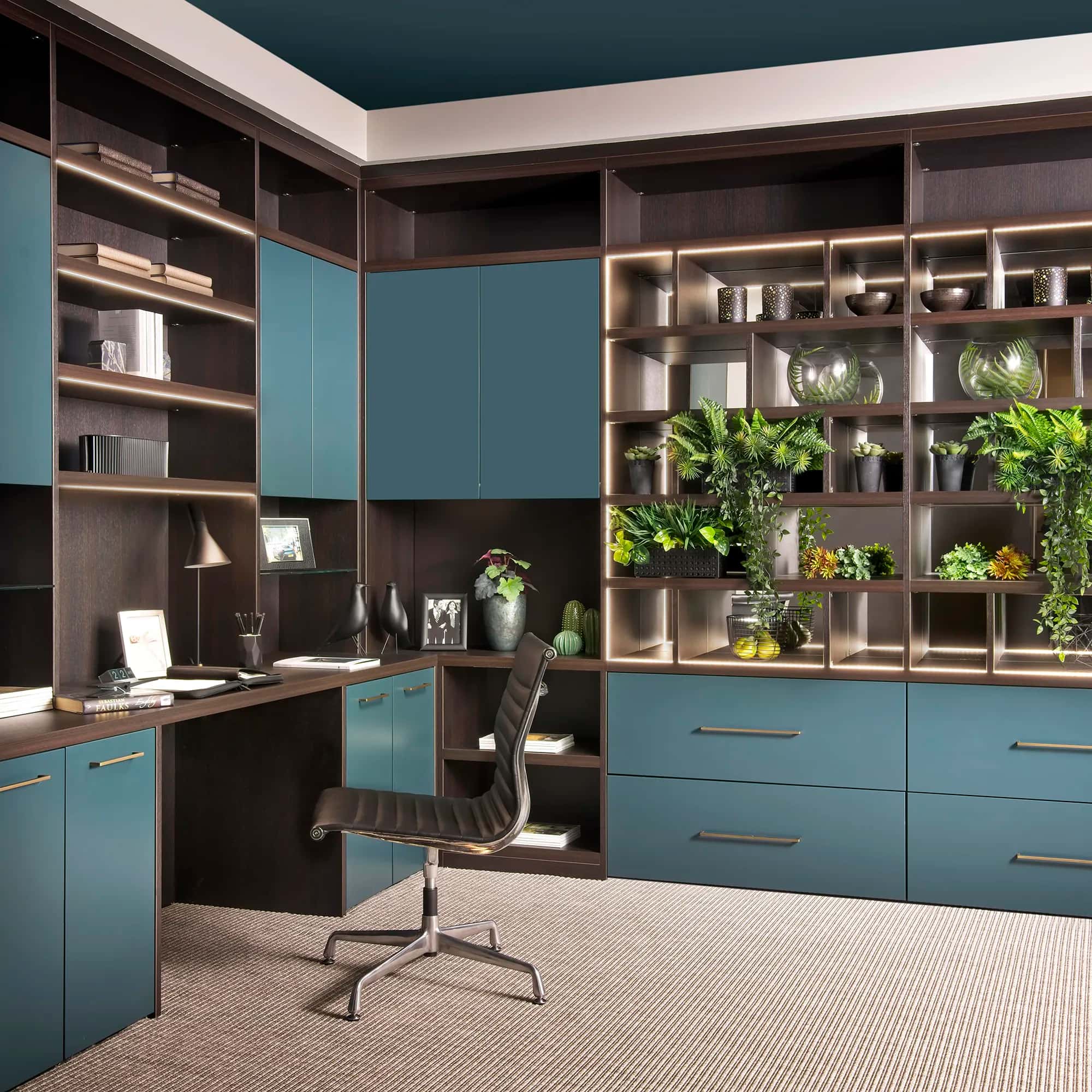 Home office with teal cabinet doors, fitted desk, LED-lit shelving and a leather chair