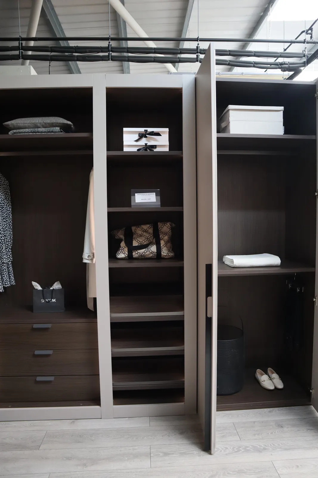 Dark wood open wardrobe with drawers, shelves and a taupe door standing ajar