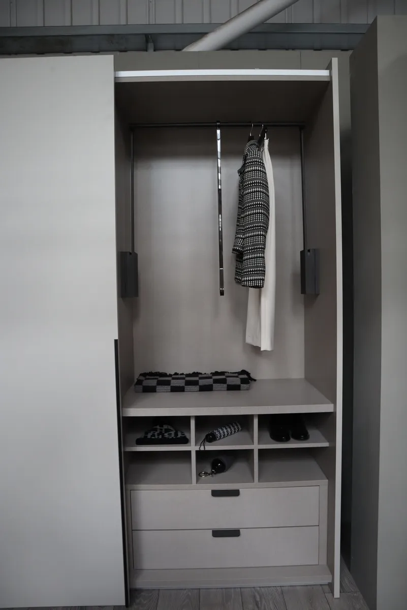 Open light grey sliding wardrobe with pull-out hanging rail, shelves and two drawers
