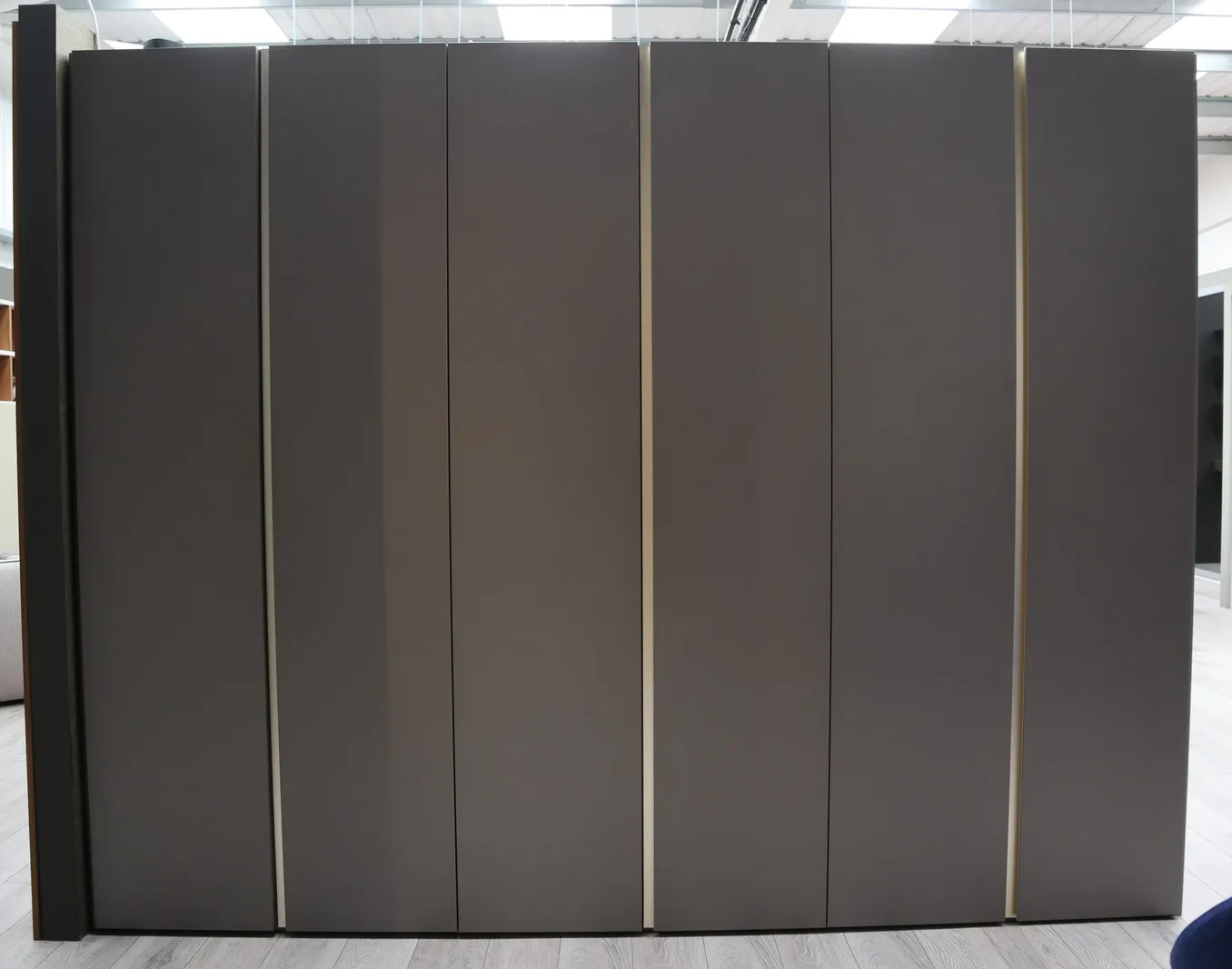 Six-door dark bronze fitted wardrobe with slim brass-effect vertical handles