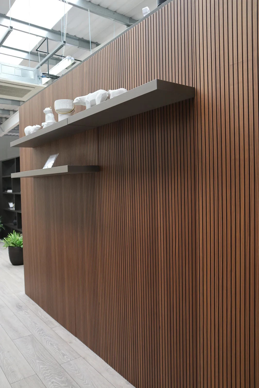 Walnut slatted wall panelling with floating grey shelves displaying white ornaments
