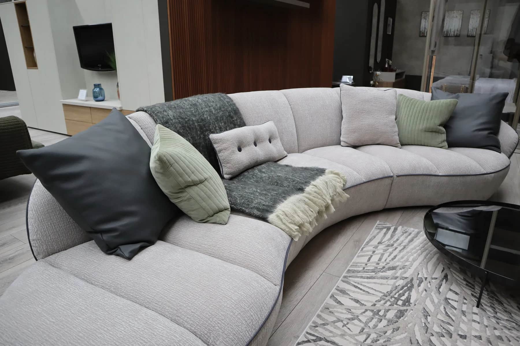 Curved light grey sofa with scatter cushions and a throw