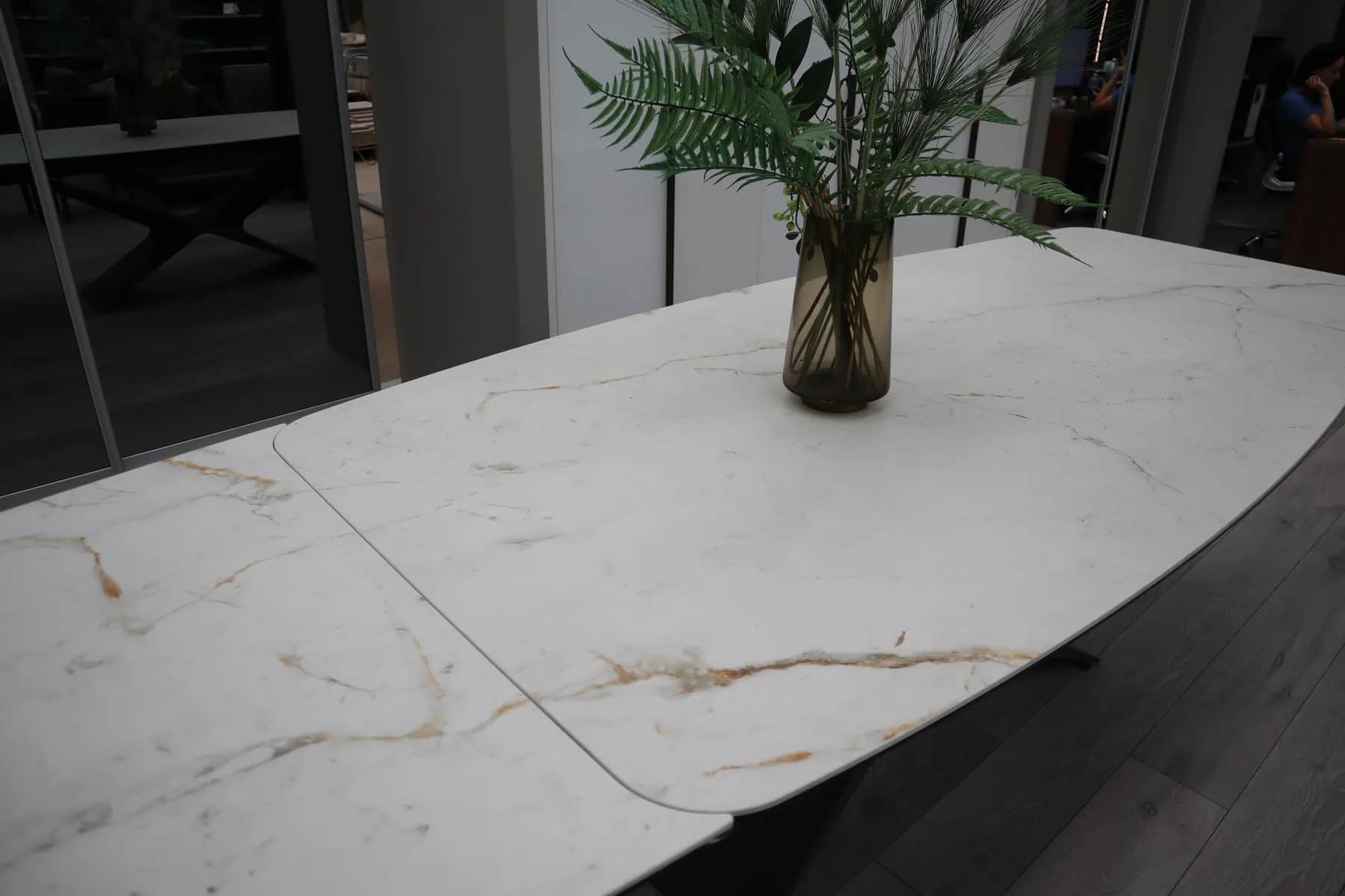 Close-up of a marble-effect extending dining table top with a vase of leaves