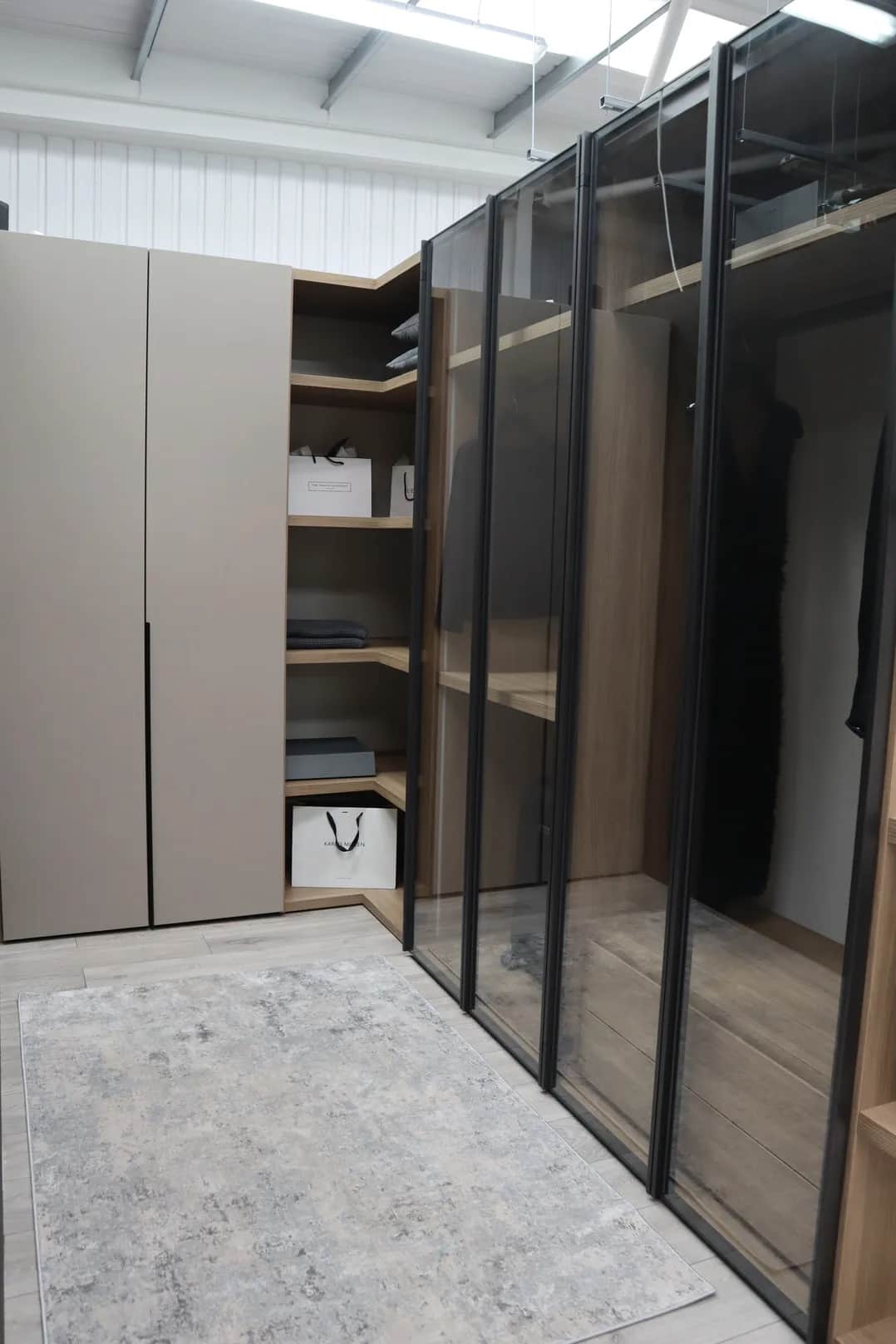 Walk-in wardrobe with glass-fronted doors, corner shelving and handbag storage