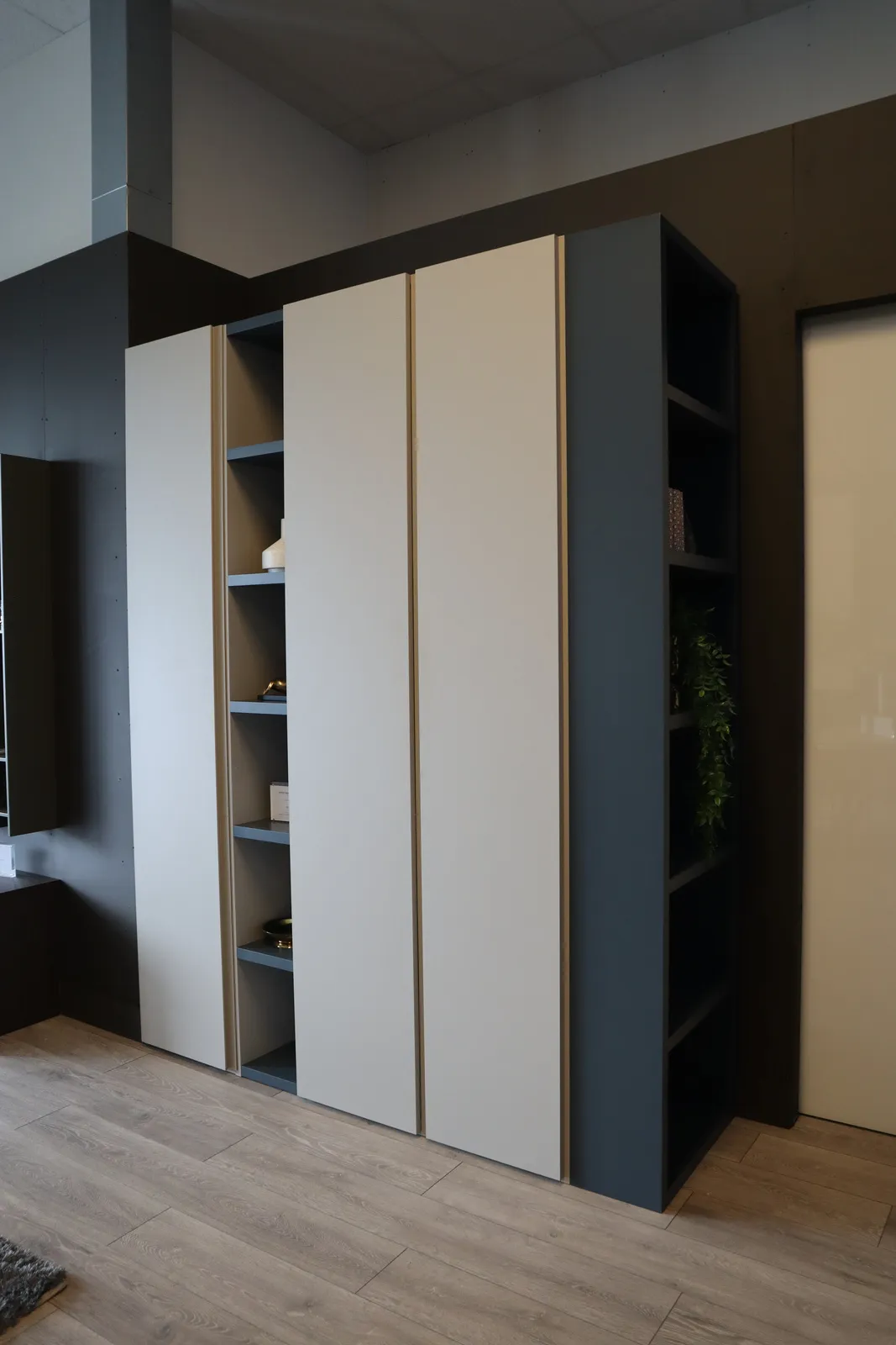 Tall wardrobe with pale doors and an adjoining dark blue open bookcase