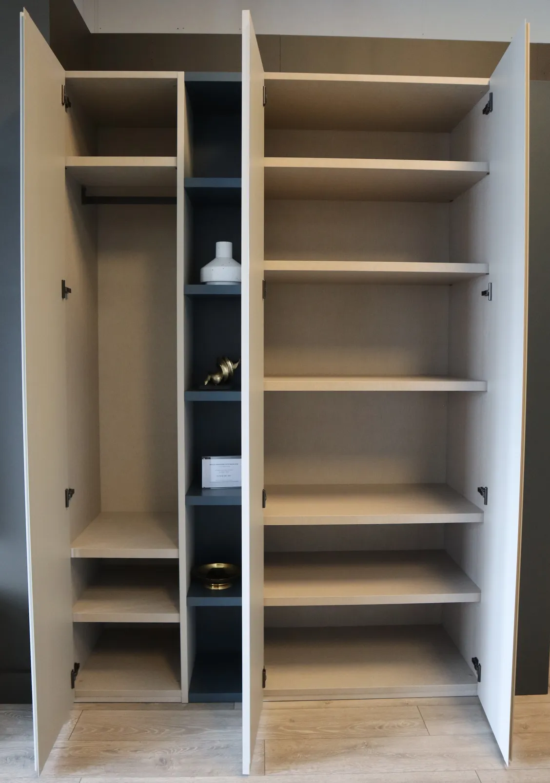 Fitted wardrobe with doors open showing shelves and a dark open storage column