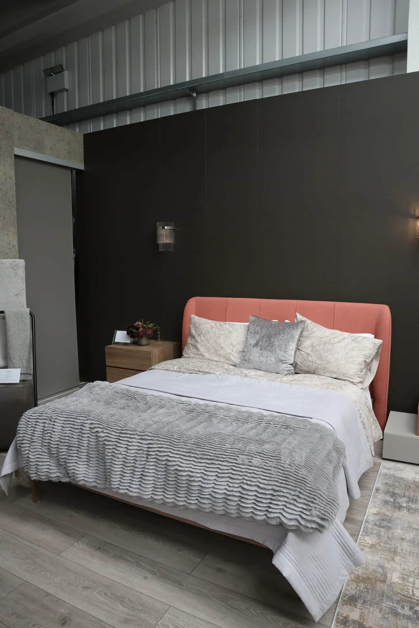 Bed with coral headboard against a dark wood panelled wall