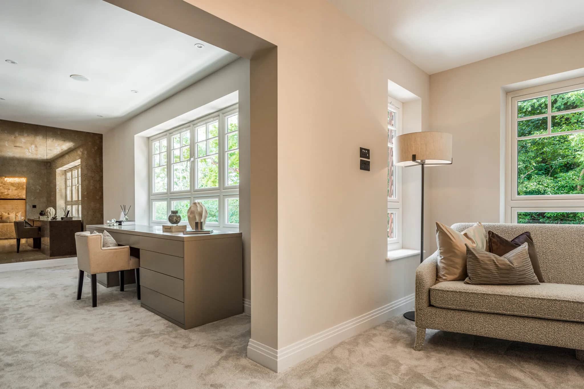 Open-plan landing with a fitted taupe dressing table and drawers beside a window and sofa