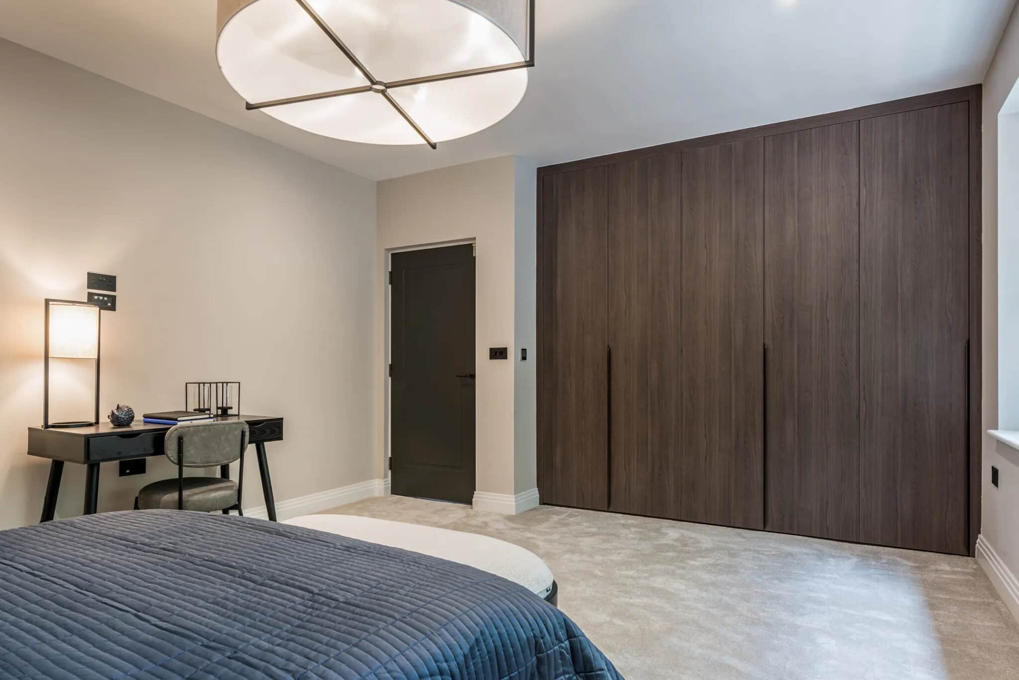 Bedroom with floor-to-ceiling dark oak fitted wardrobes with slim recessed handles and a desk