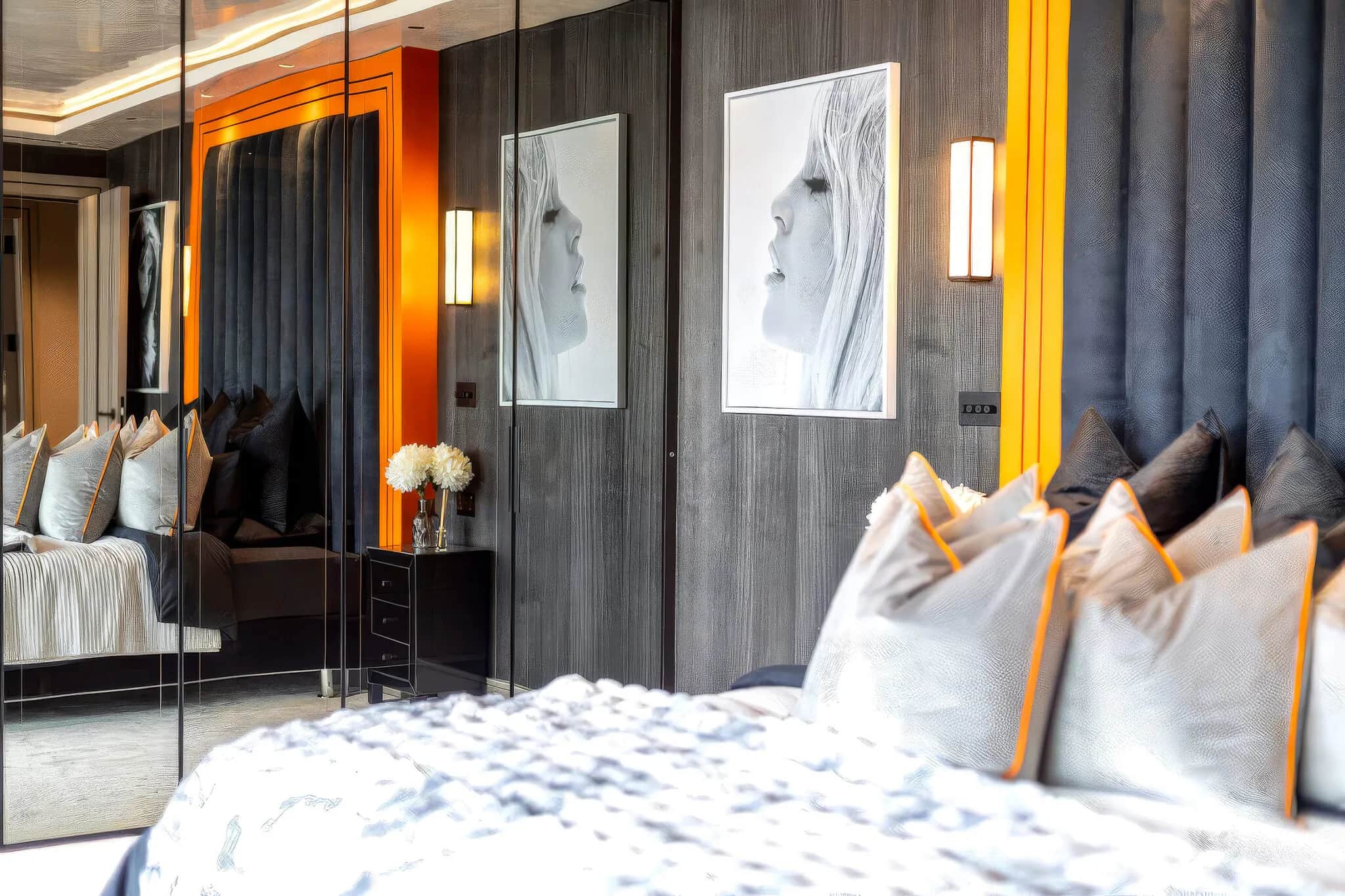 Bedroom with orange-framed padded headboard, wood-panelled wall and mirrored wardrobe doors