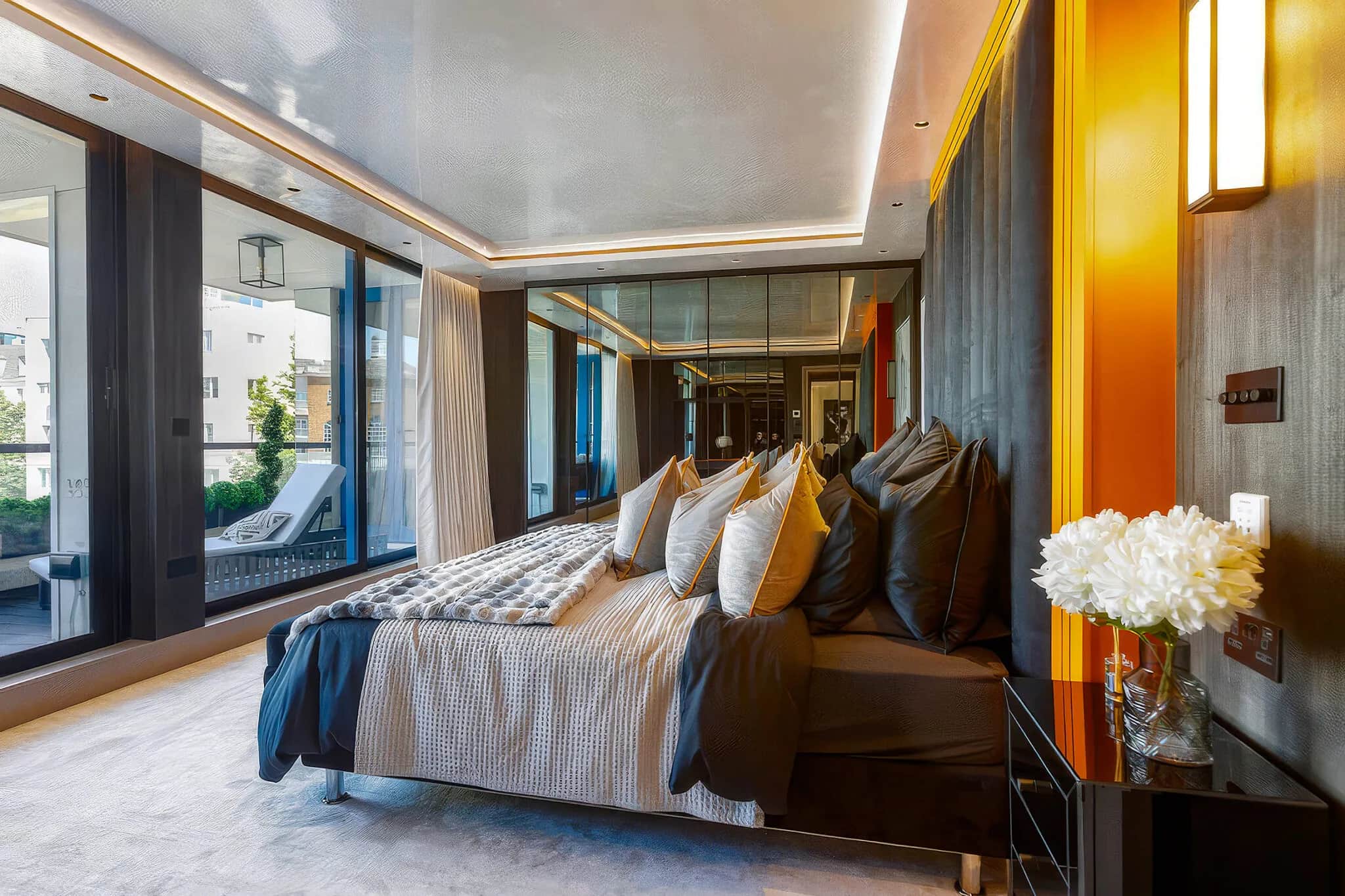 Bedroom with orange accent panels, dark wood wall cladding and floor-to-ceiling balcony windows