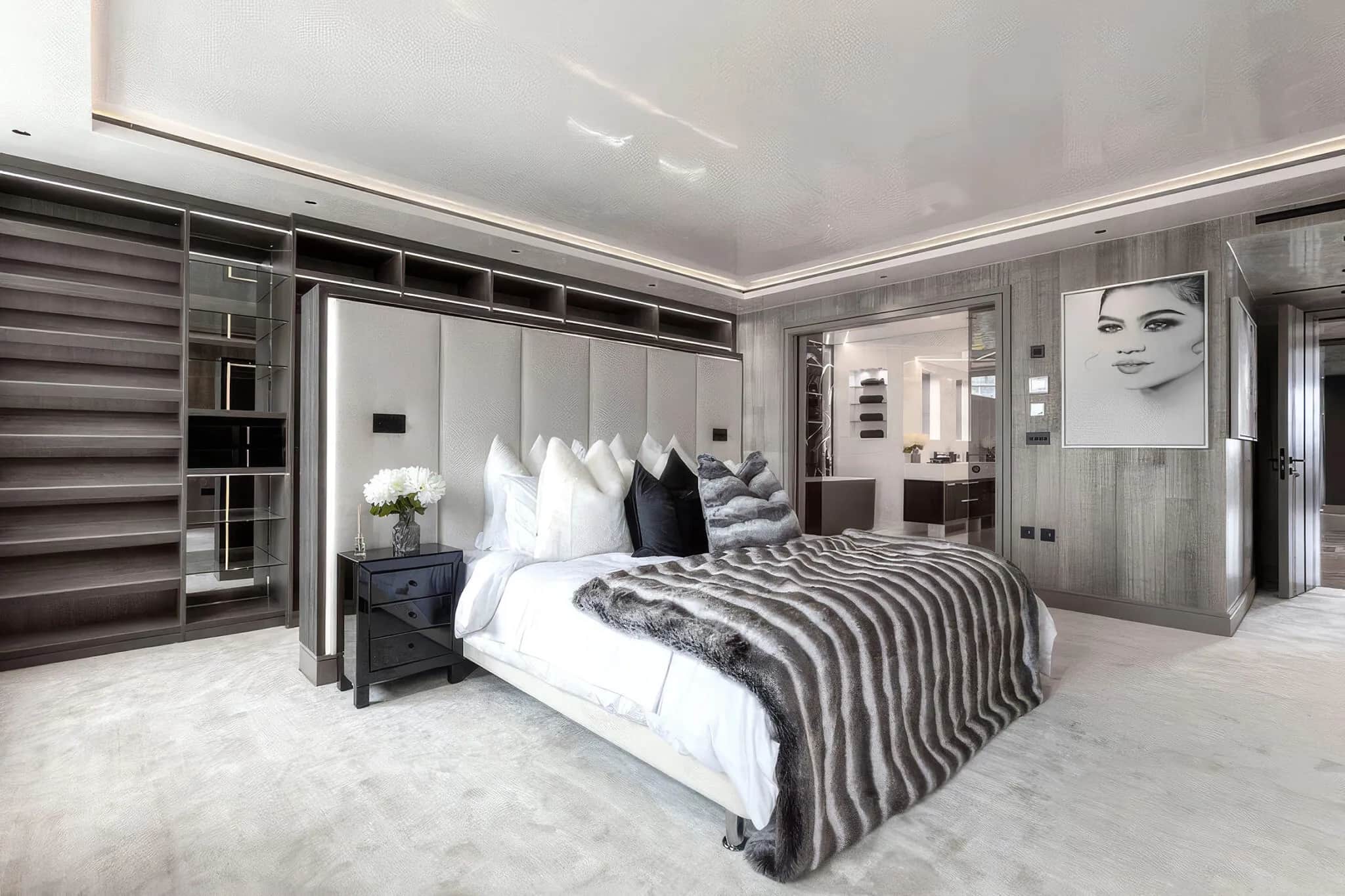 Master bedroom with grey padded headboard, fitted open shelving and fur bed throw