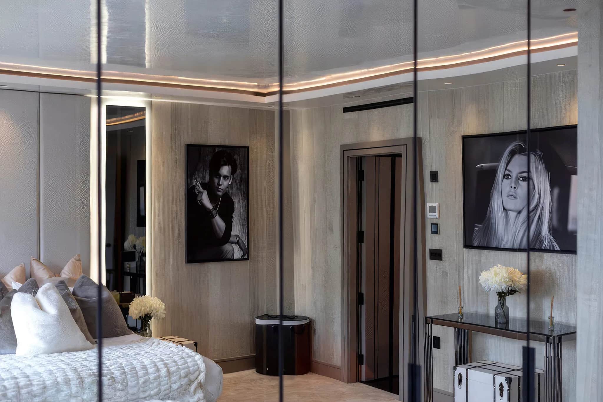 Bedroom with mirrored wardrobe doors reflecting the room, pale wood panelling and framed portraits