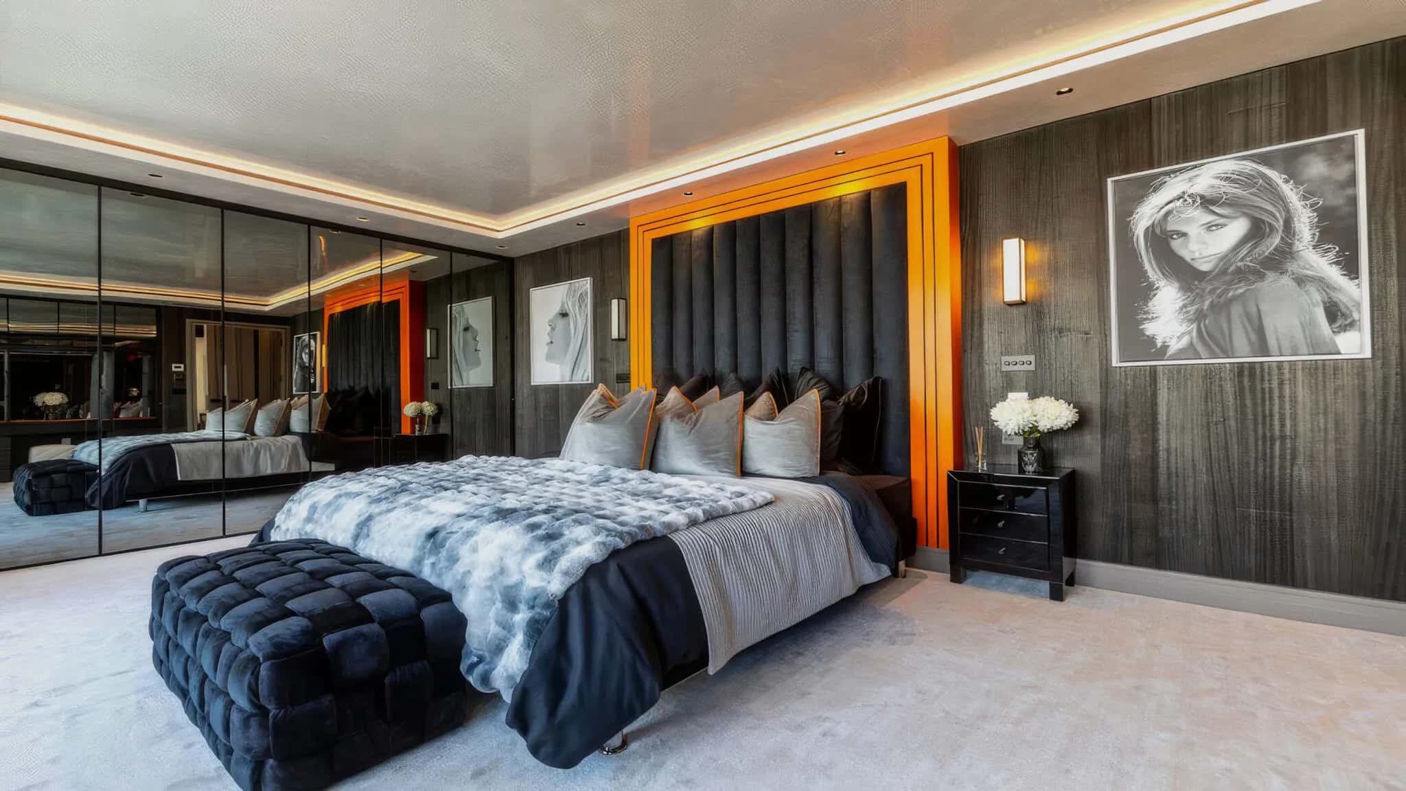 Bedroom with fitted mirrored wardrobes and an upholstered headboard framed in orange lighting