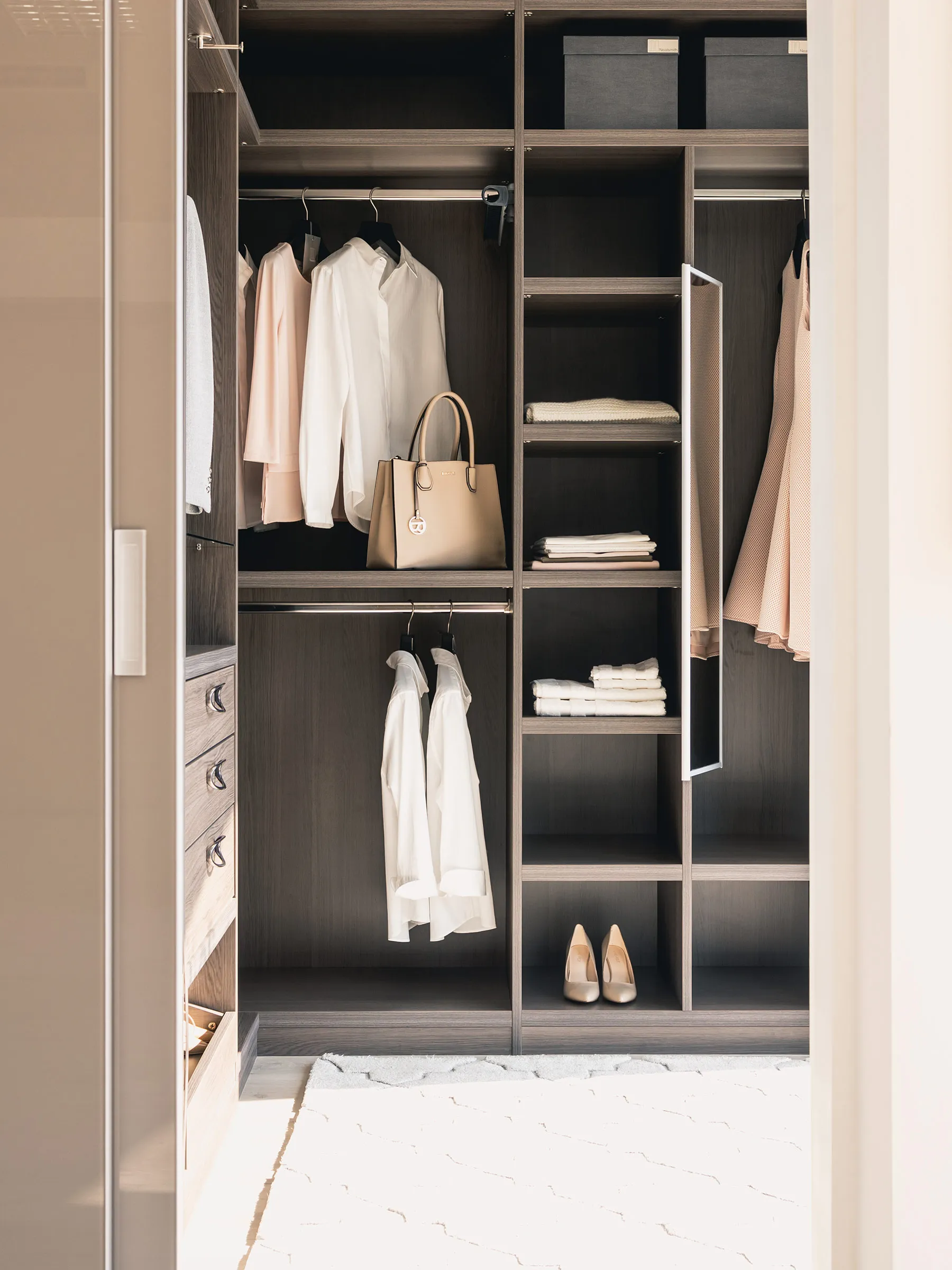 Walk-in wardrobe with dark oak shelving, hanging rails, drawers and a mirrored side panel