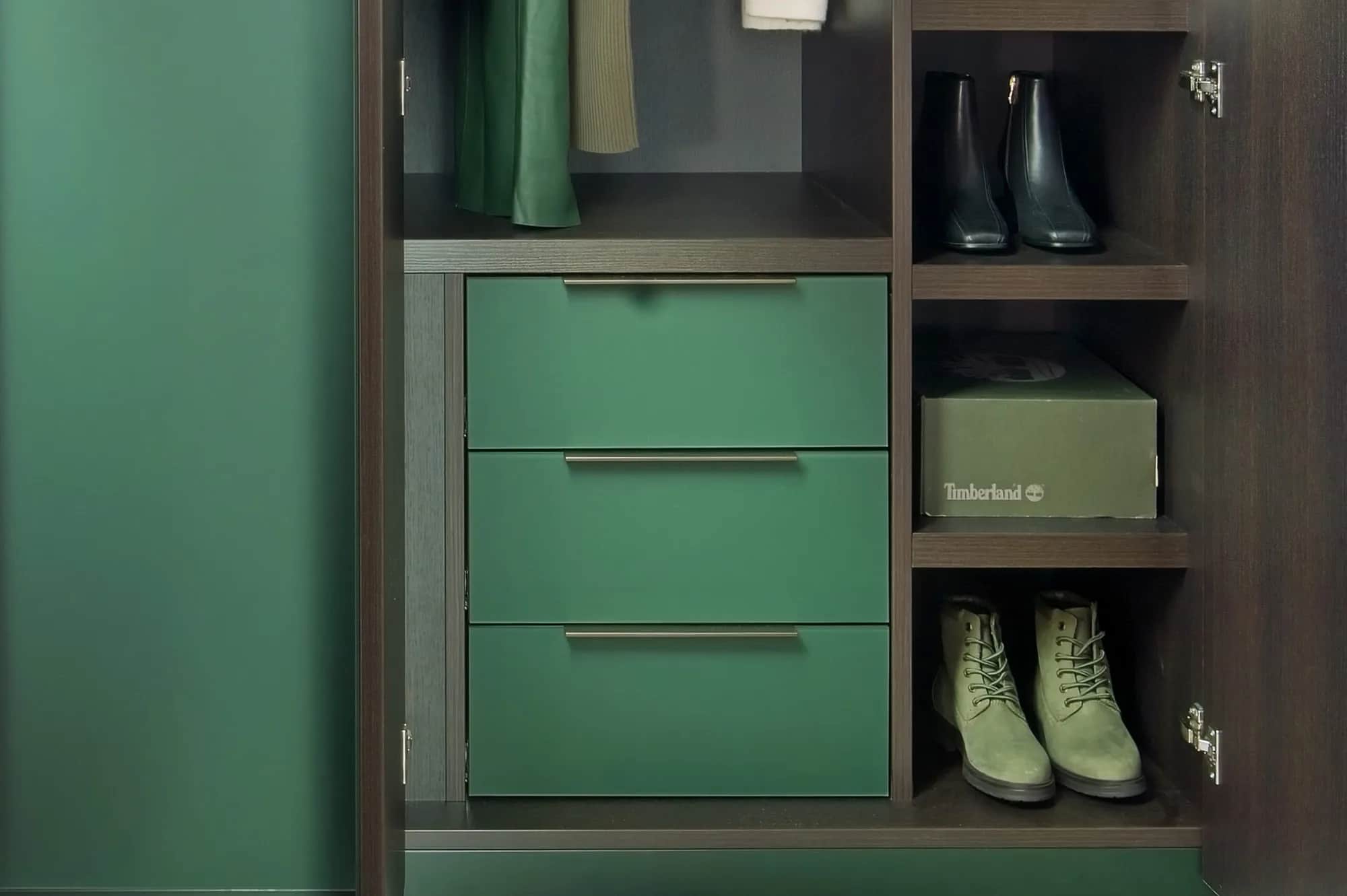 Green lacquer drawers and shelving inside a fitted wardrobe, with boots and a shoe box